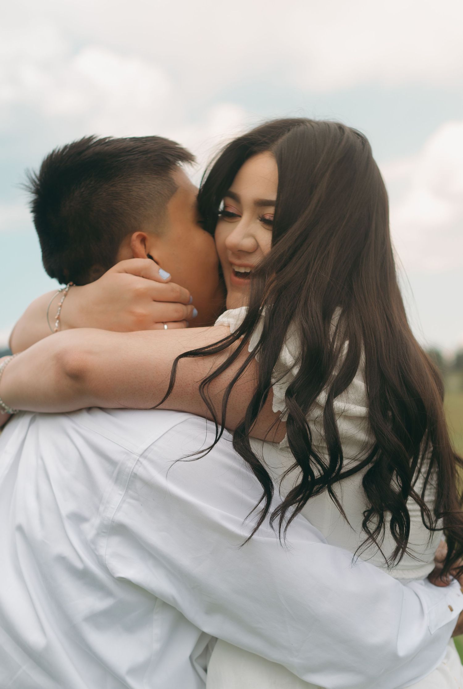 Candid romantic moments captured between two people embracing against a bright sky.