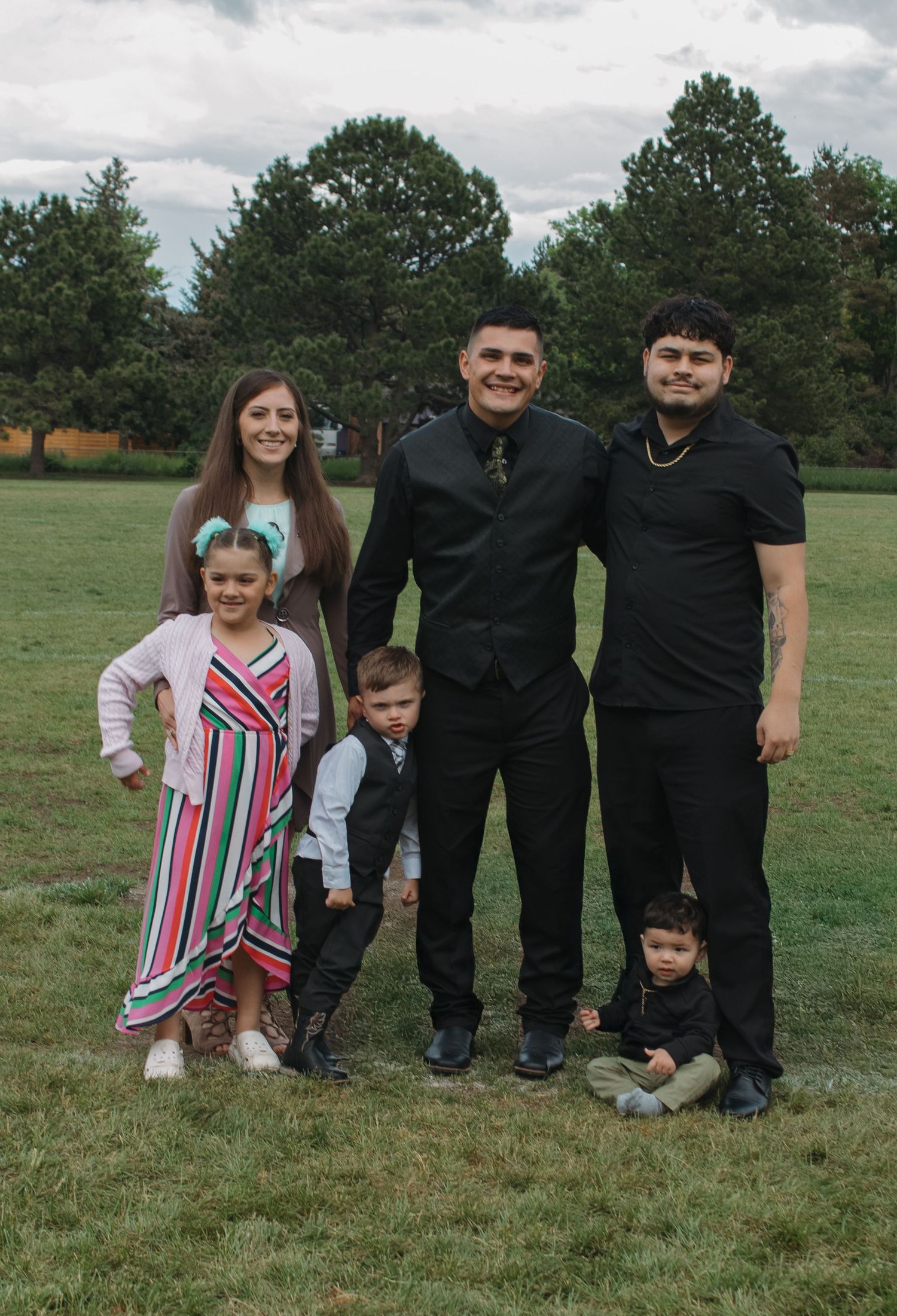 Group photo of formally dressed people posing together on grass field.
