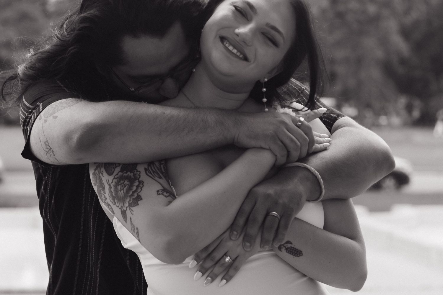 A candid black and white photo capturing a joyful embrace outdoors.