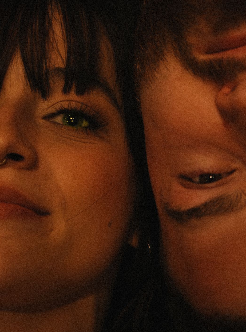 Extreme close-up artistic portrait showing dark eyes and bangs in moody lighting.