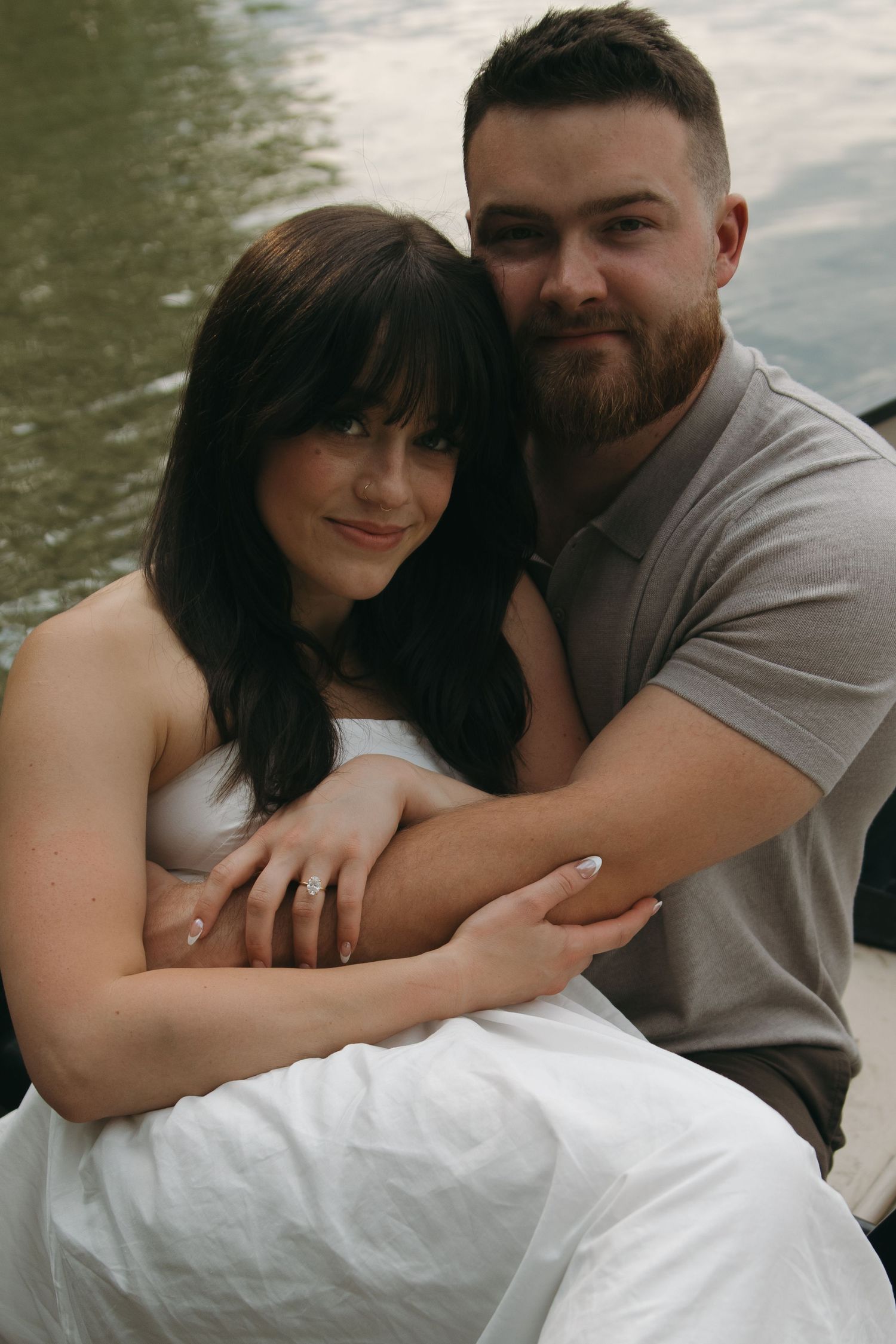 Romantic couple shares intimate embraces while nestled together on white linens by a lake.