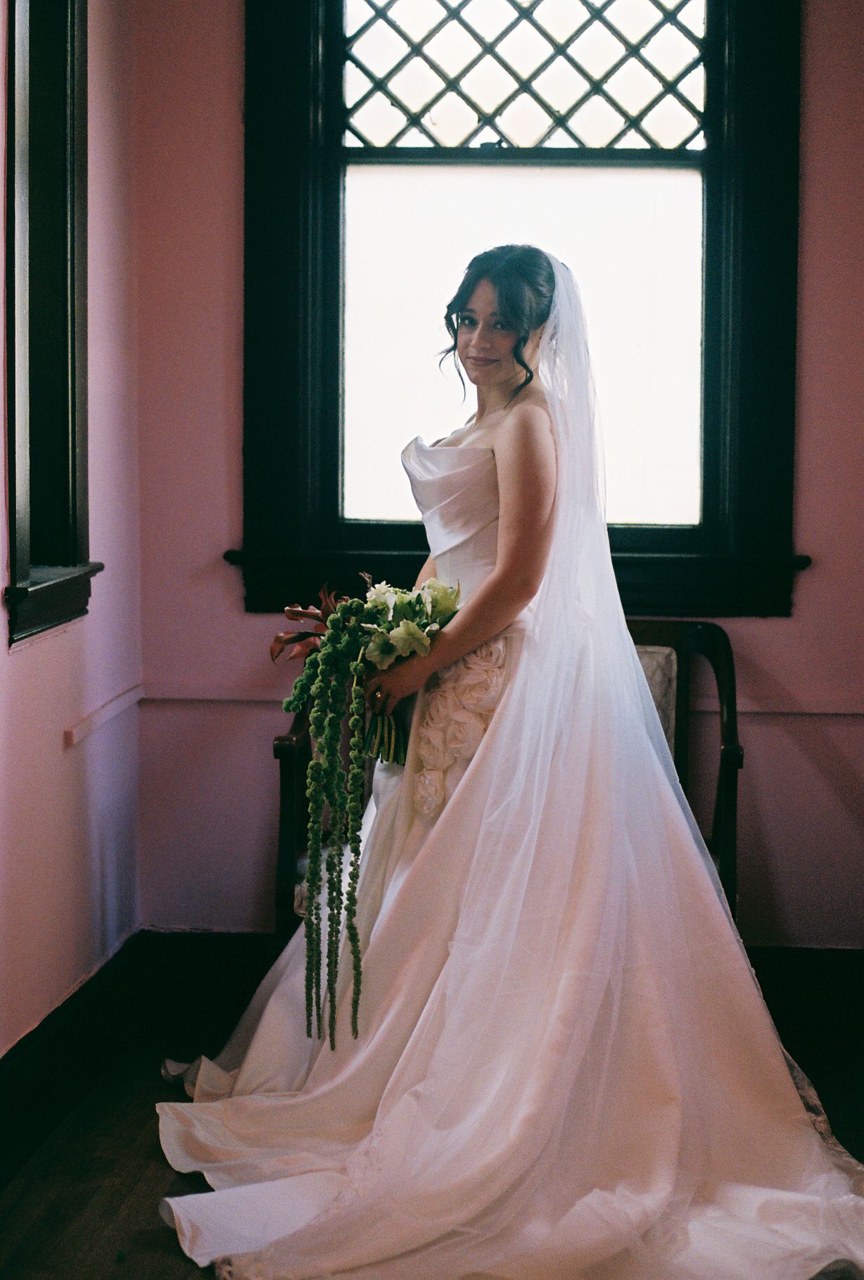 A flowing white wedding gown and veil captured in sequence near vintage windows with natural light.