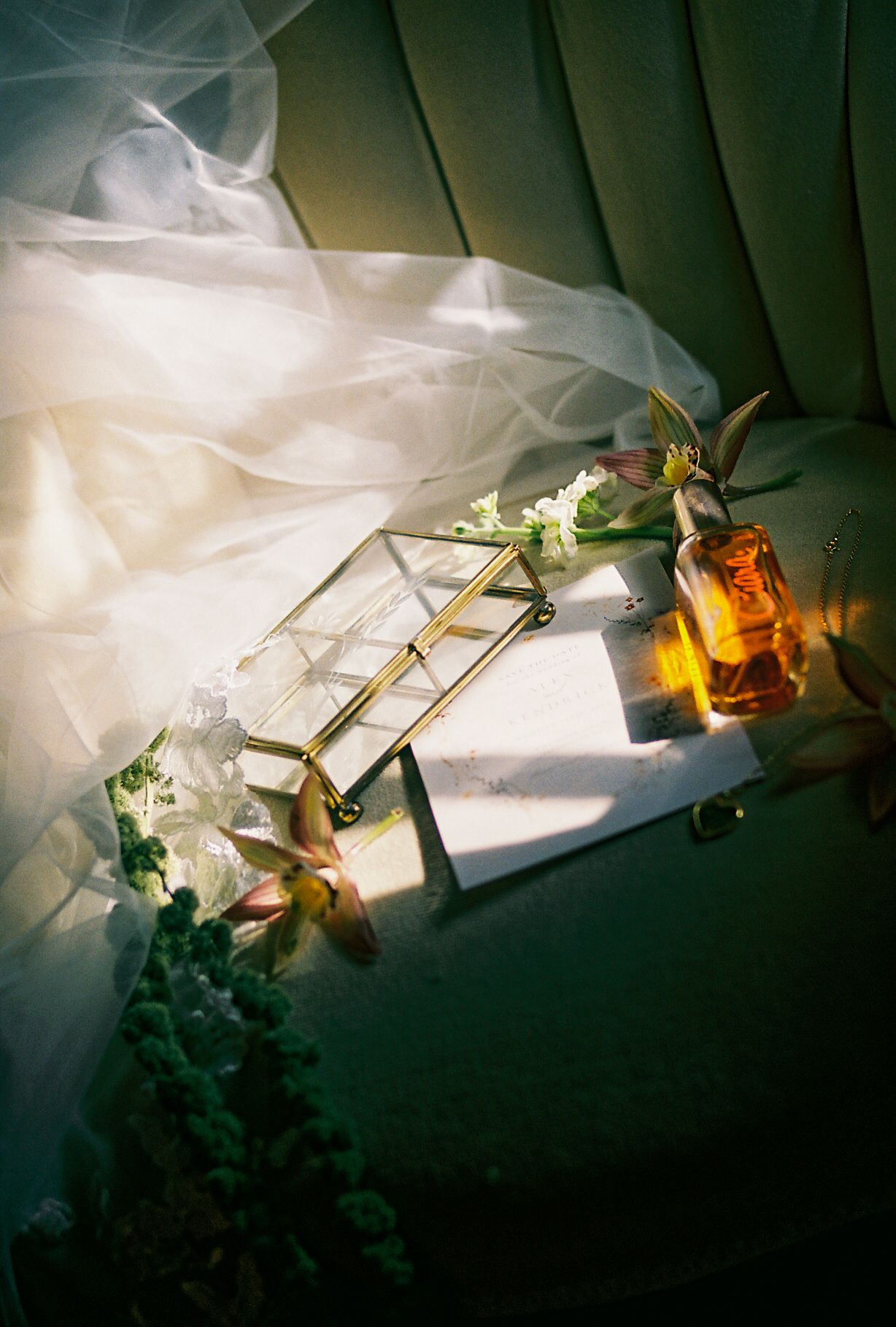 Artistic still life of wedding accessories with amber bottle and white fabric in dramatic lighting.