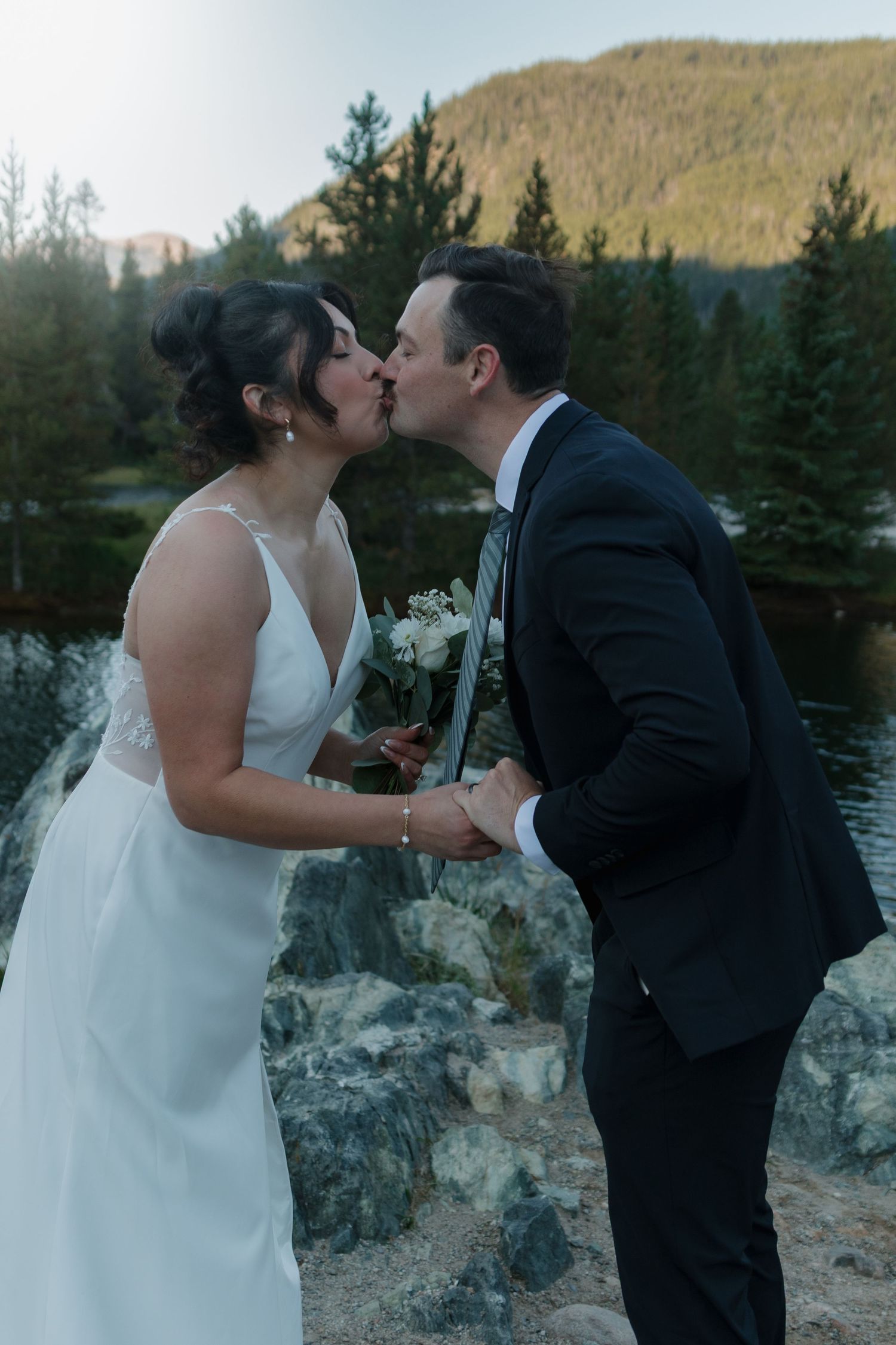 A romantic moment captured between newlyweds by a scenic mountain lake.
