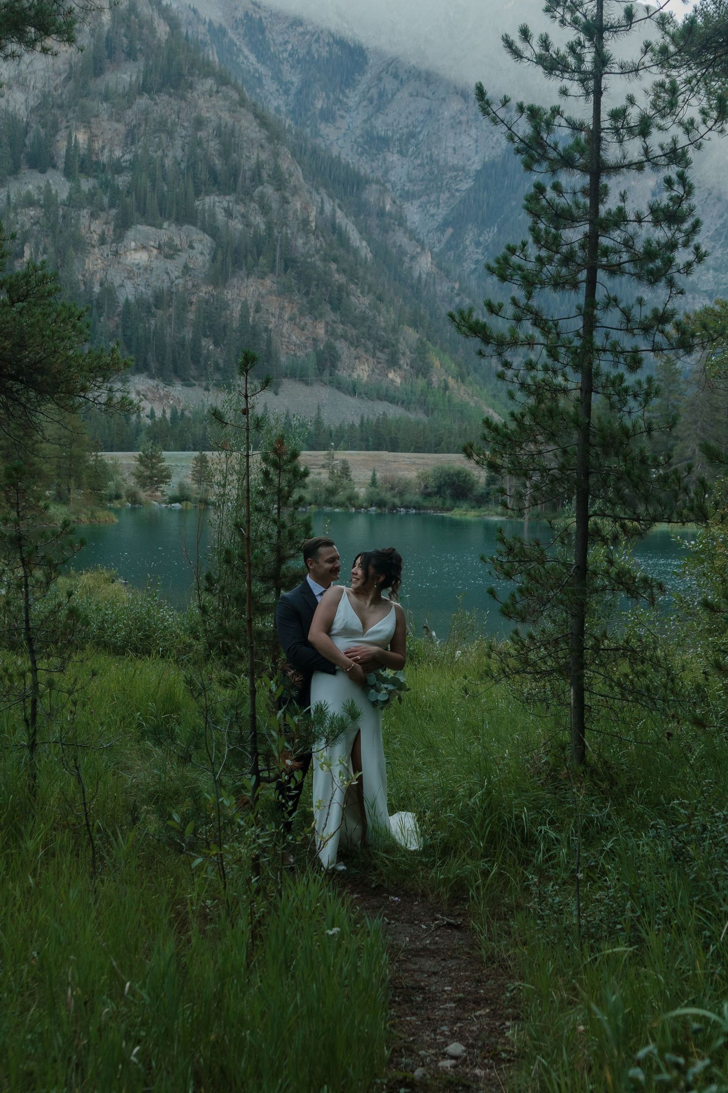 A scenic mountain lake wedding photoshoot showcases love amidst evergreen forests and rugged peaks.