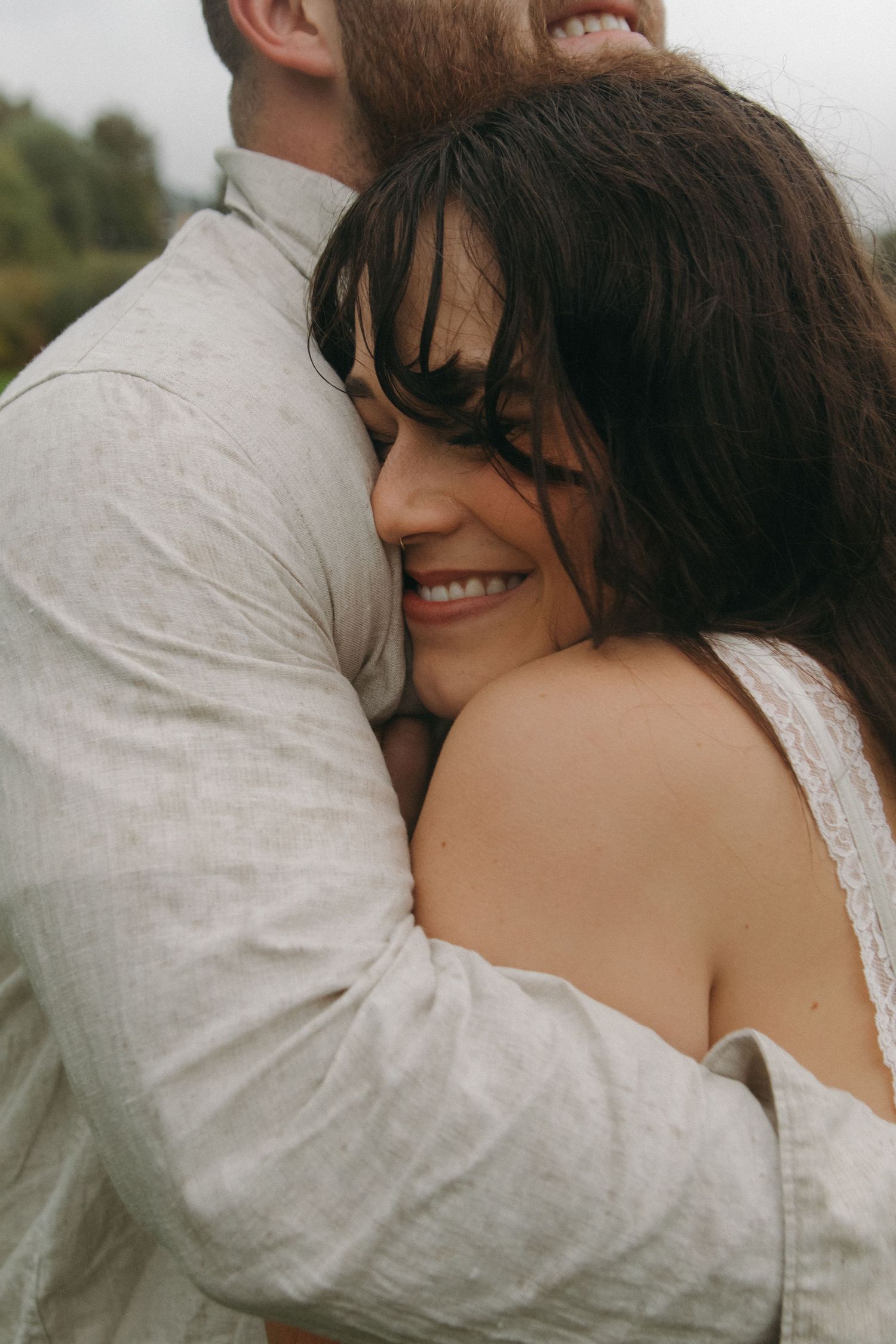 An intimate moment captured between a couple in light-colored clothing during an outdoor photoshoot.