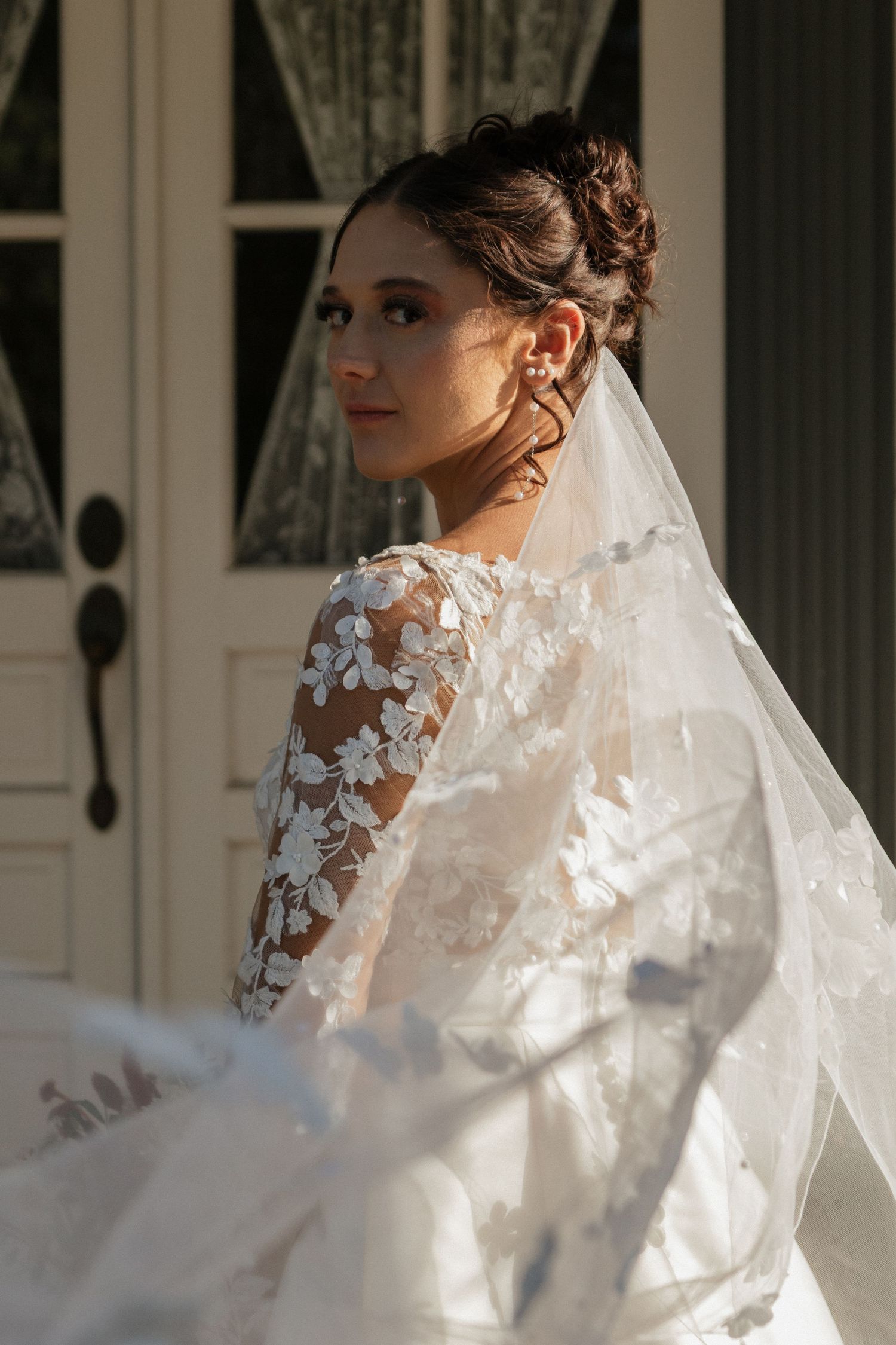 Close-up detail of delicate lace wedding dress and veil in natural light.