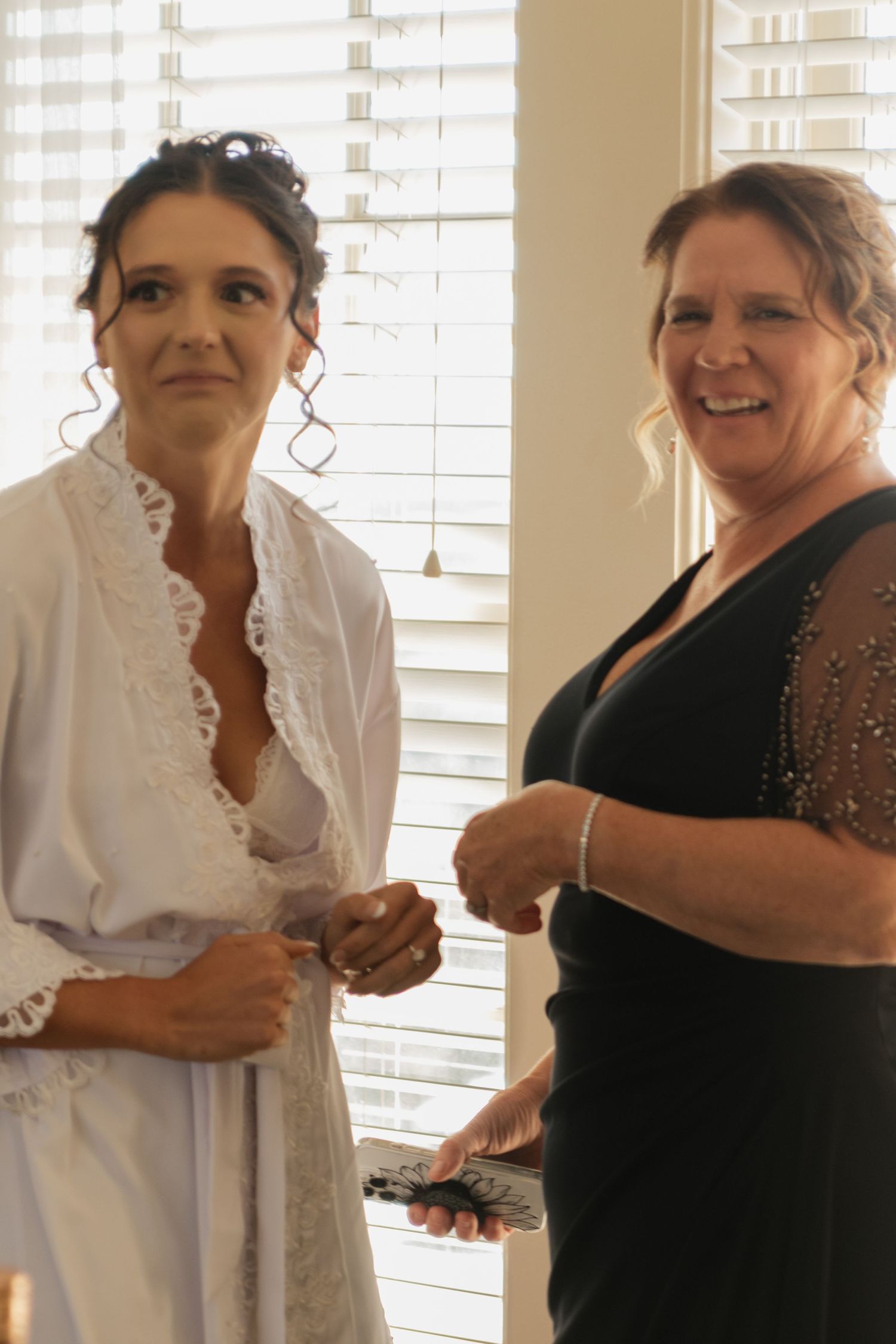 Wedding preparation moment showing excited interactions in a bright indoor setting.