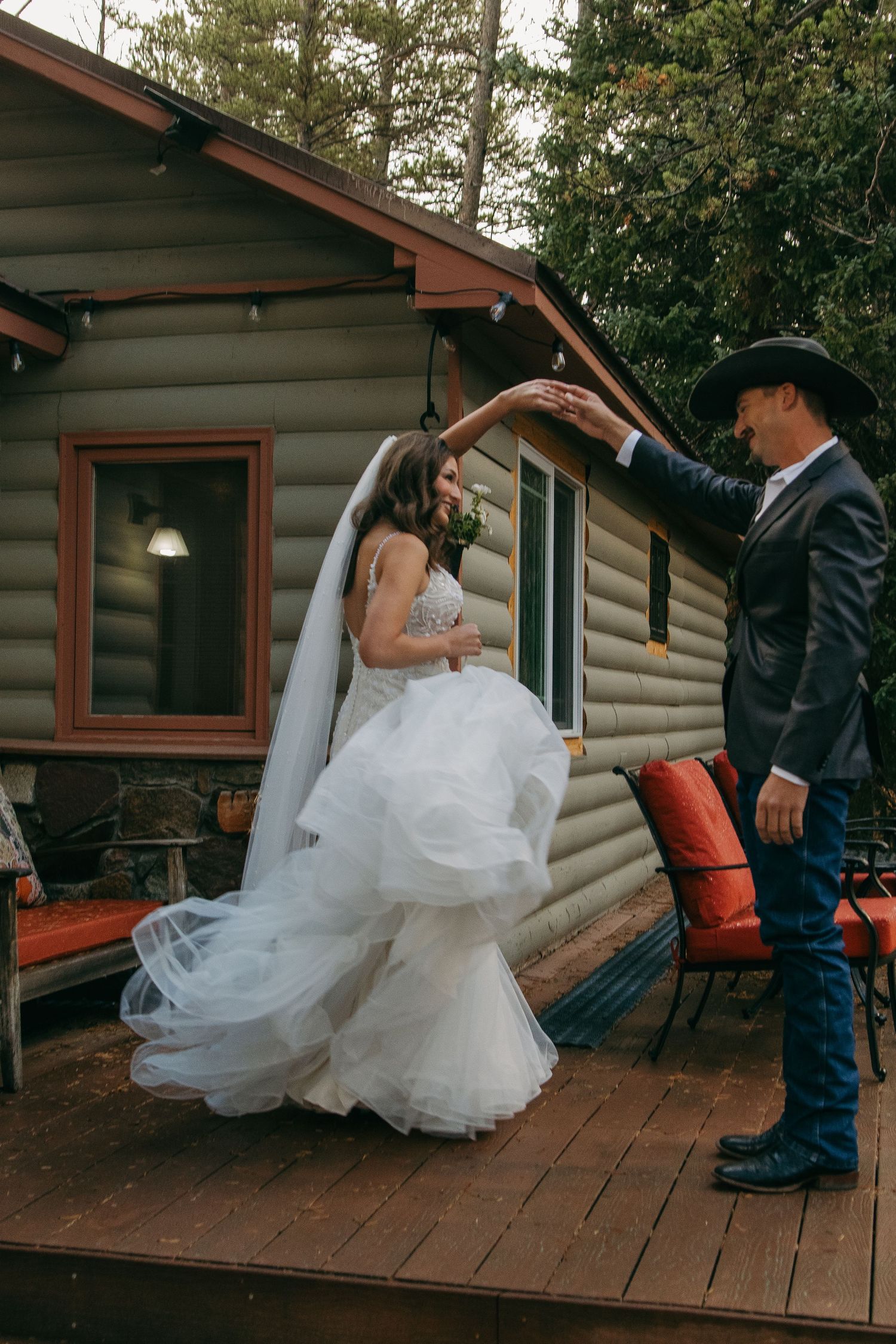 Bride twirling in her dress on a wooden cabin porch.