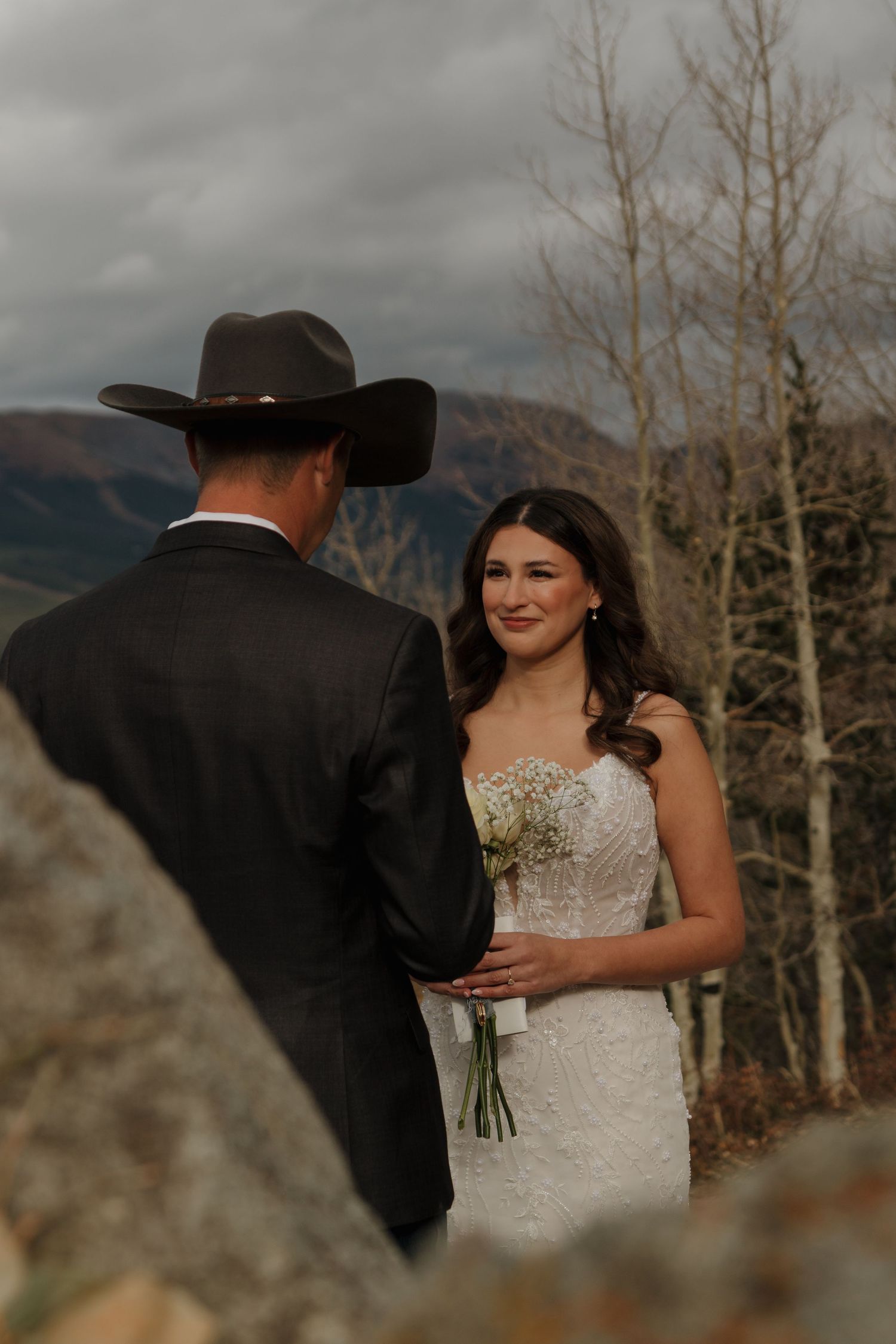 An emotional first look moment captured against a mountain backdrop with bare trees.