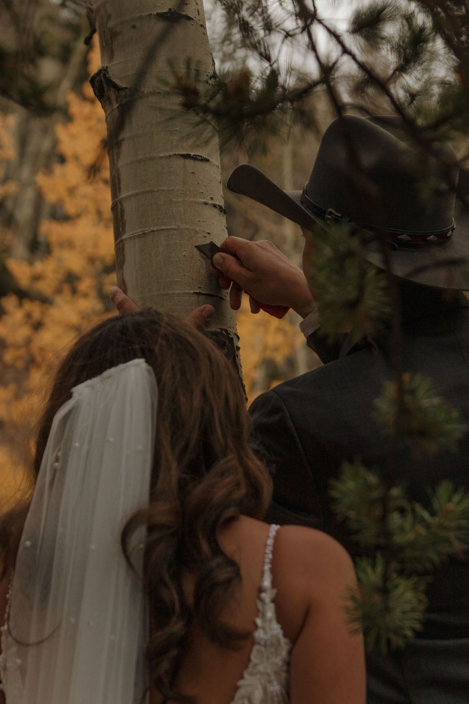 A romantic wedding moment captured against autumn trees and natural scenery.