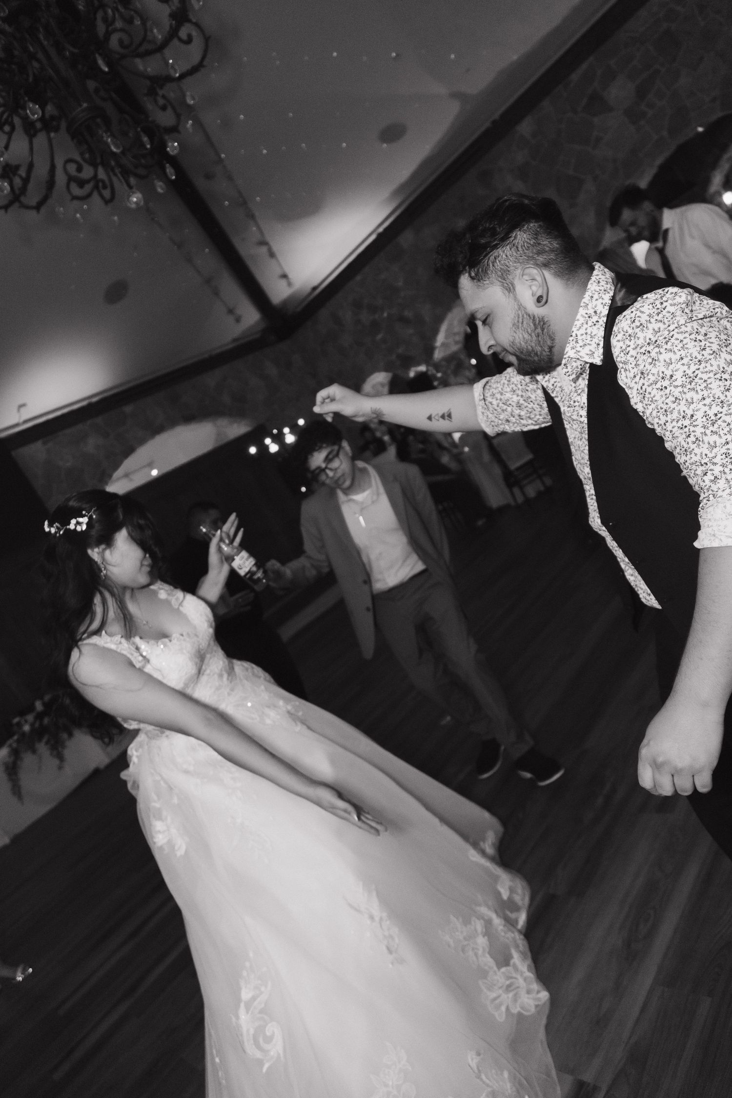 Black and white photo of bride and groom sharing an energetic first dance at wedding reception.