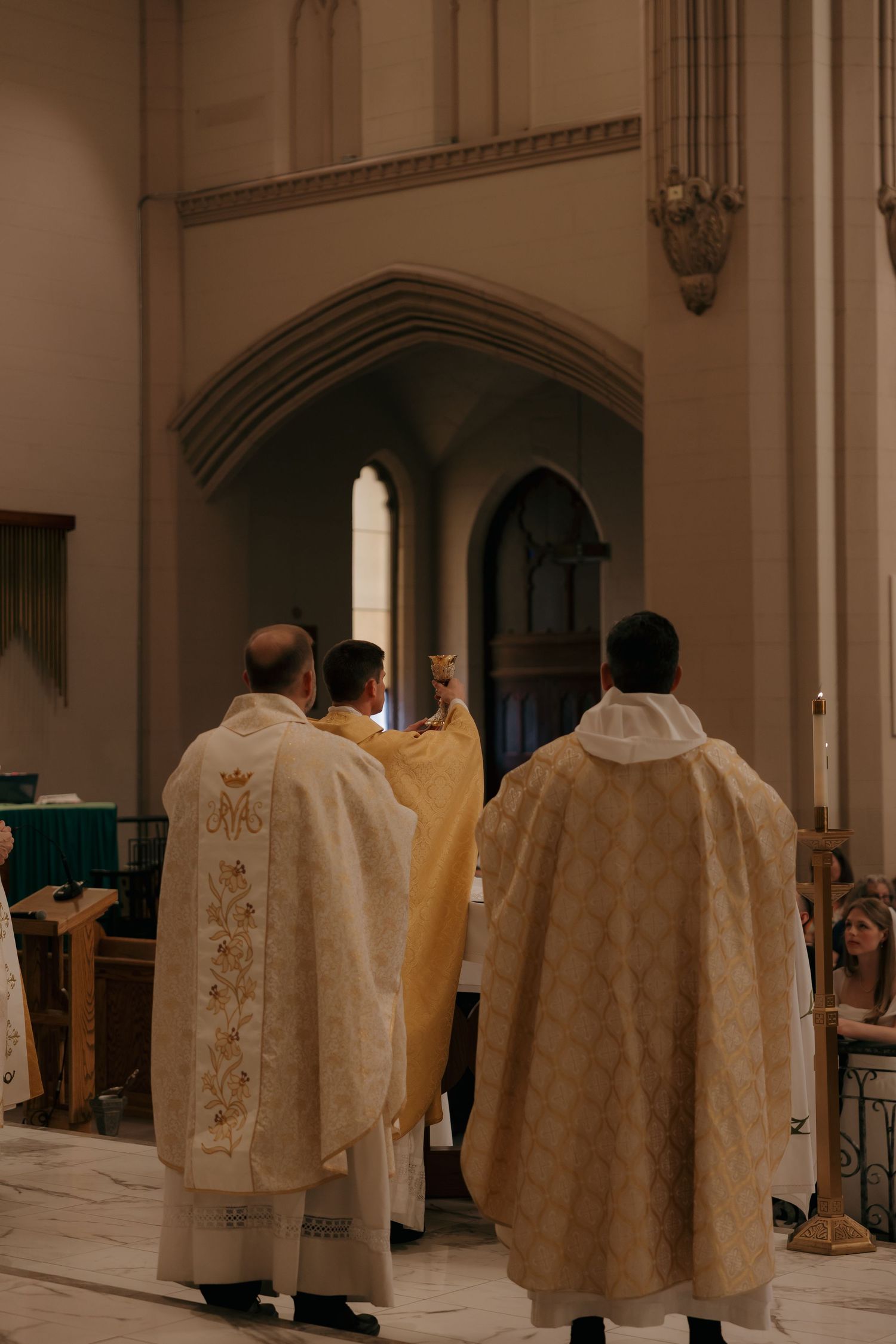 Catholic priests in ornate vestments performing wedding ceremony at church altar.