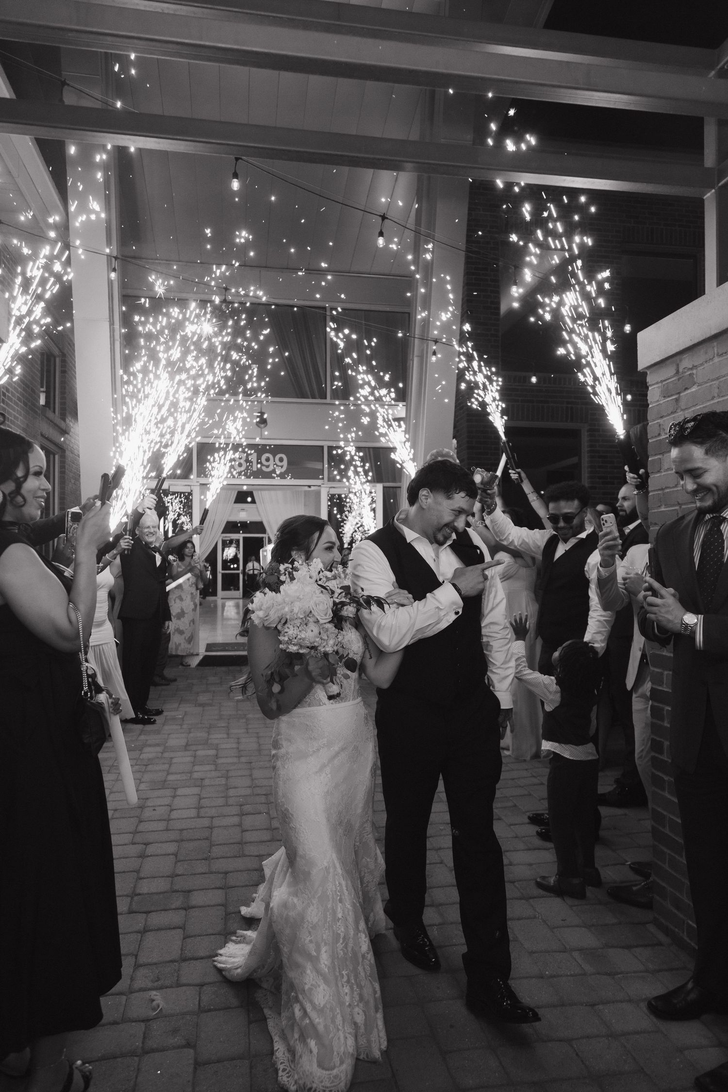 Black and white photo of bride and groom kissing during sparkler send-off exit.