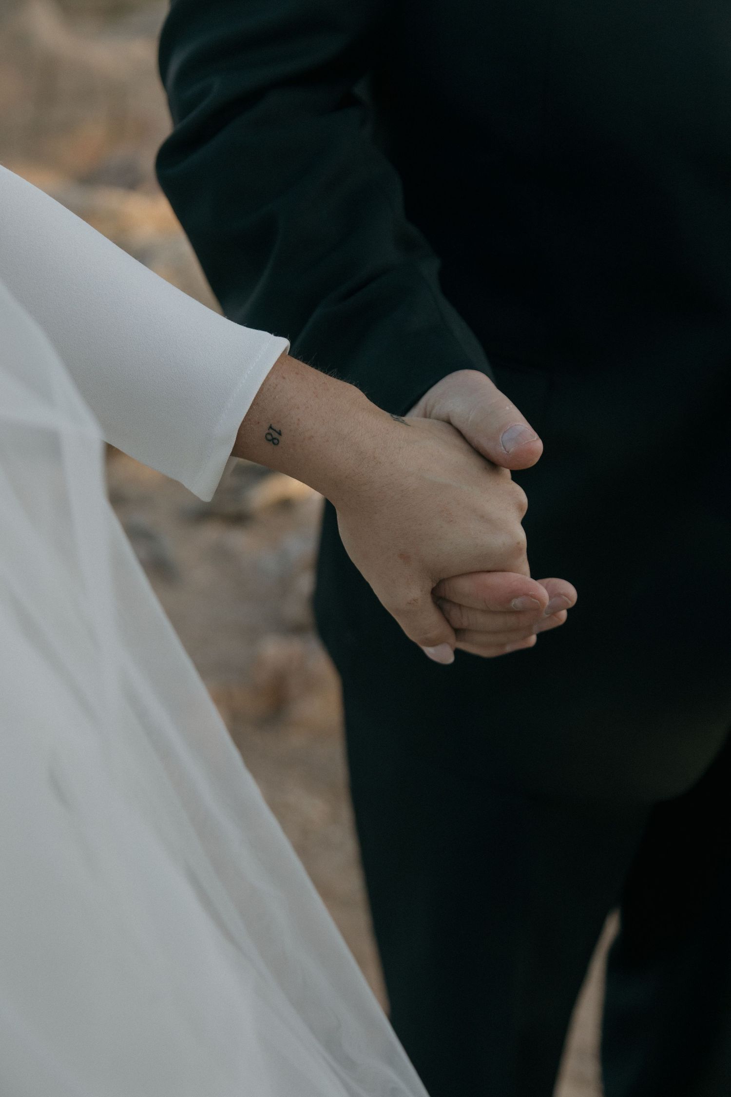 Bride and groom hold hands during outdoor mountain wedding ceremony at dusk.