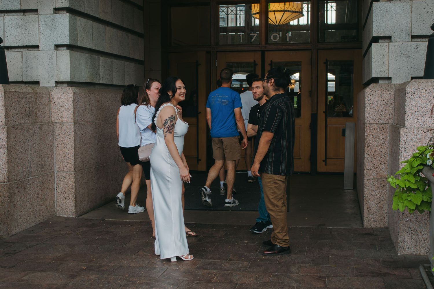 A gathering of people in formal attire inside a grand building entrance with stone columns.