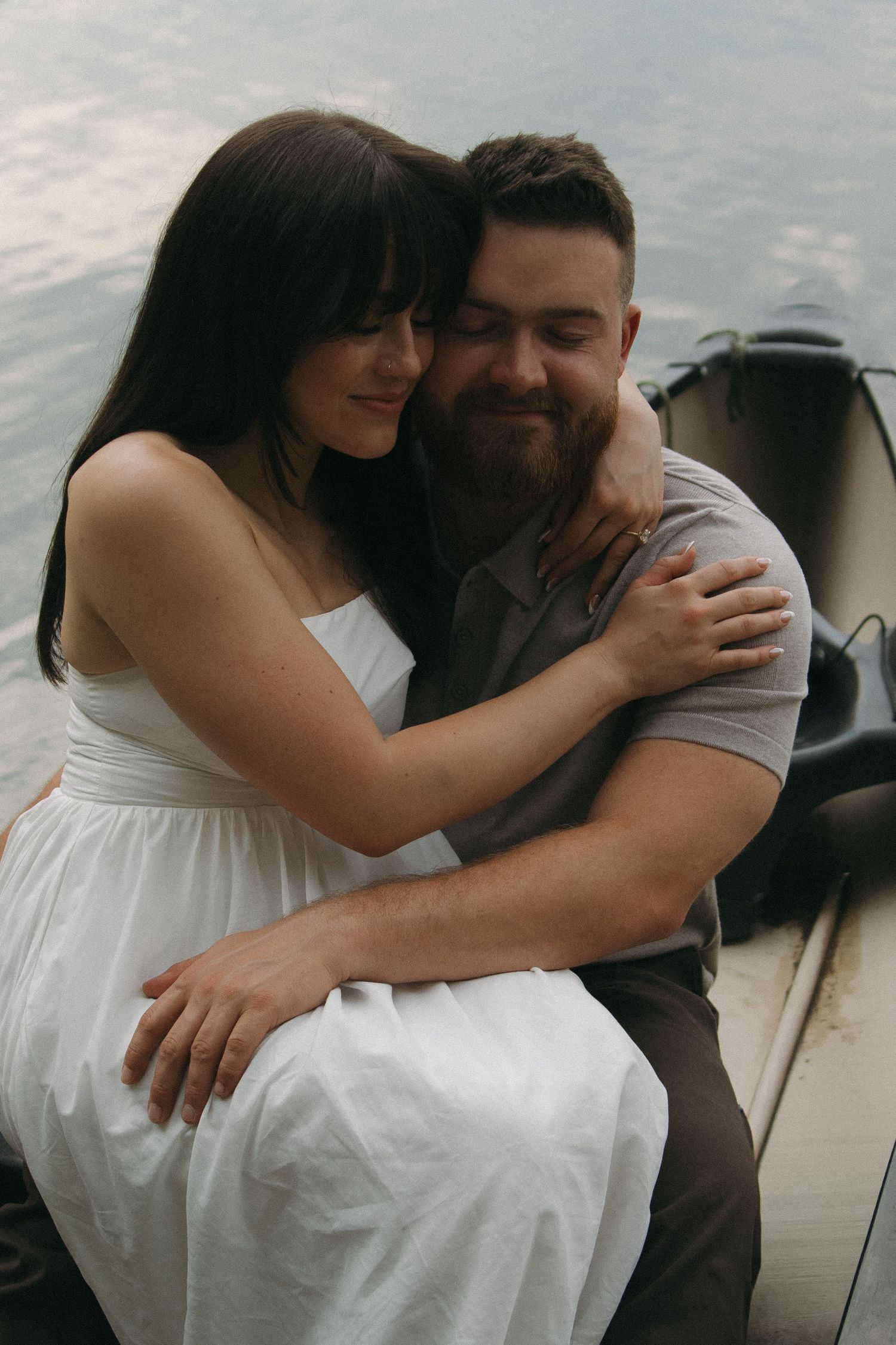Romantic couple sharing an intimate embrace outdoors in a dreamy sunset setting by the water.