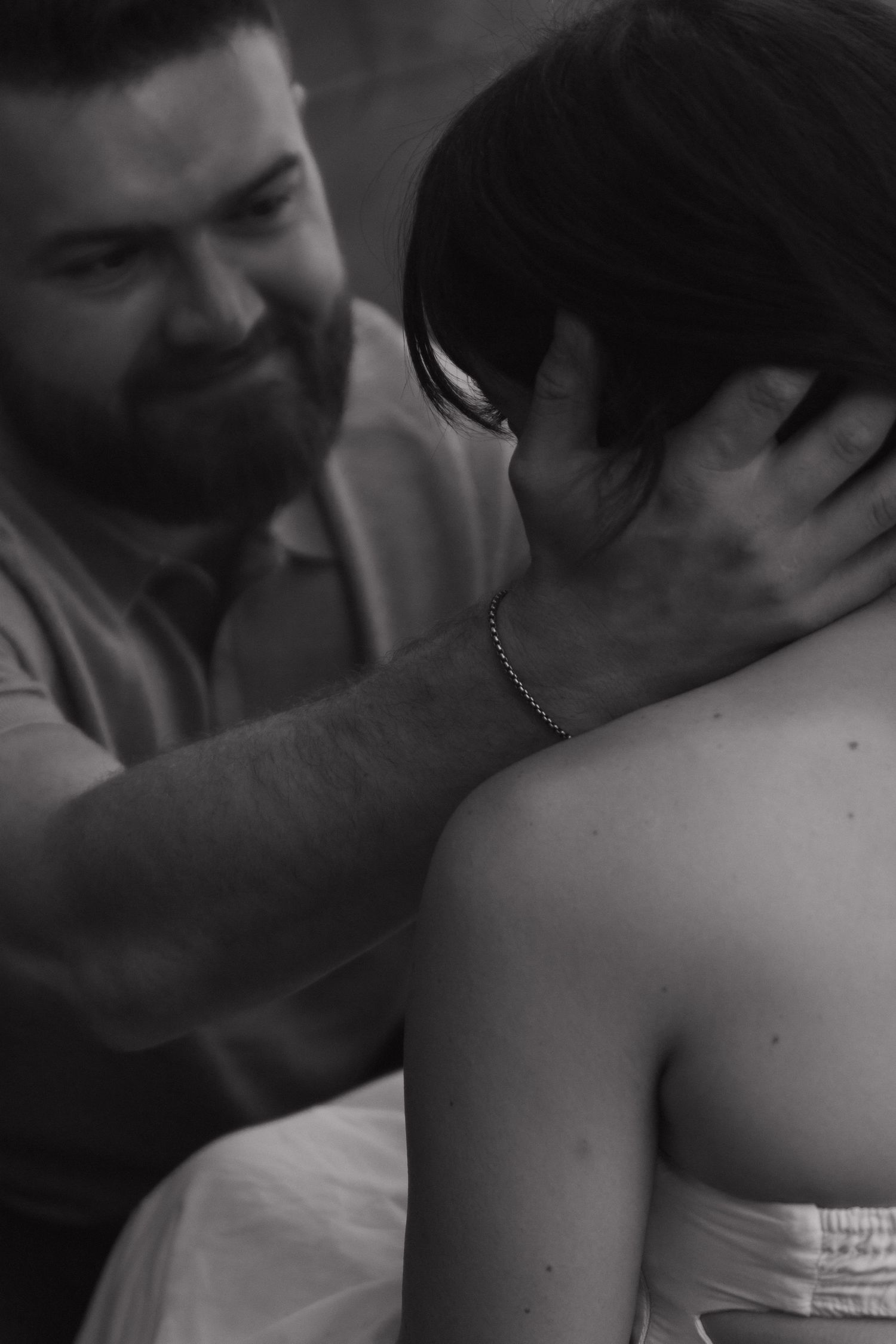An intimate black and white portrait captures a tender moment between a couple.