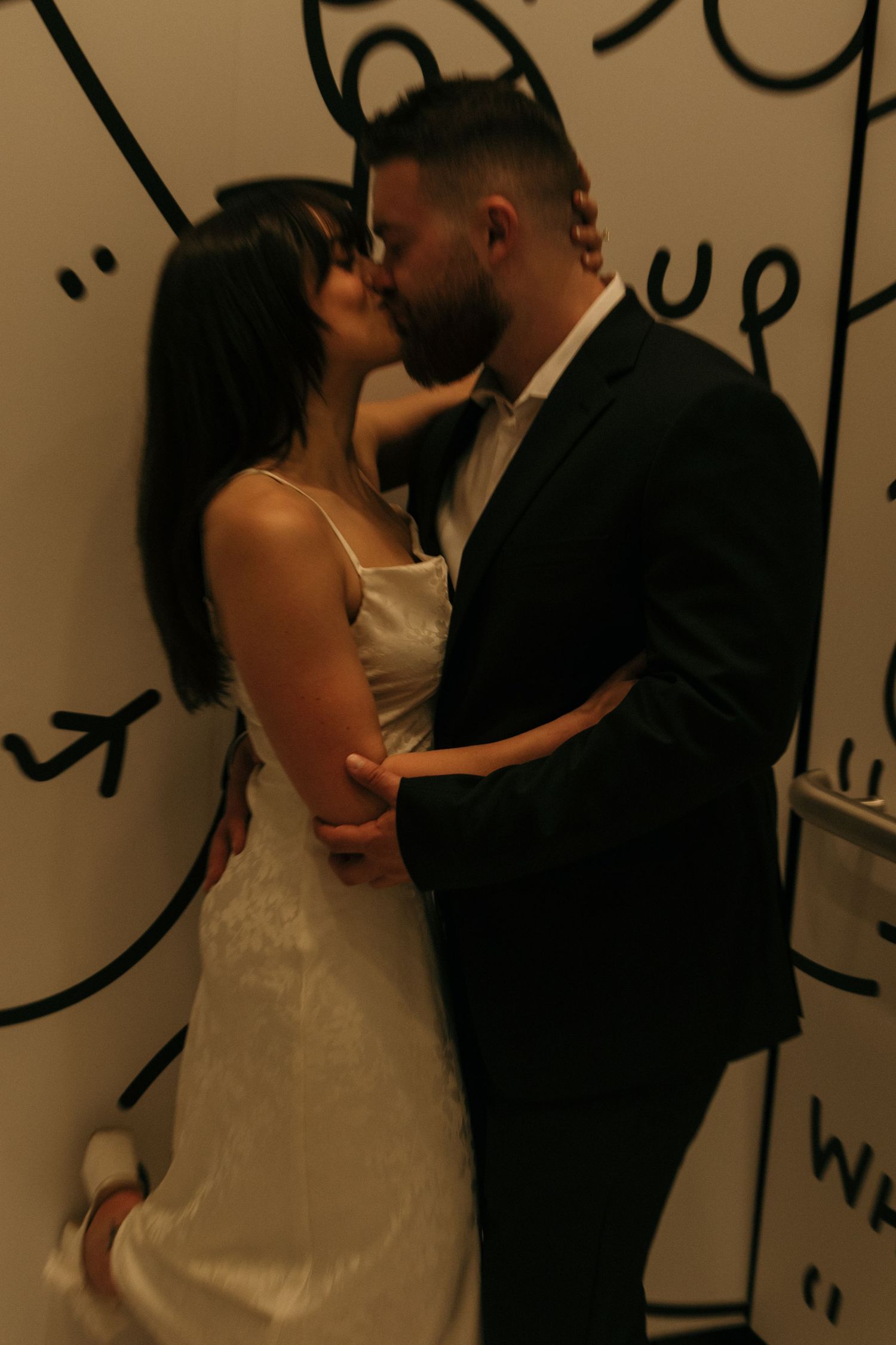 A couple sharing a romantic dance moment against a wall with artistic graffiti designs.