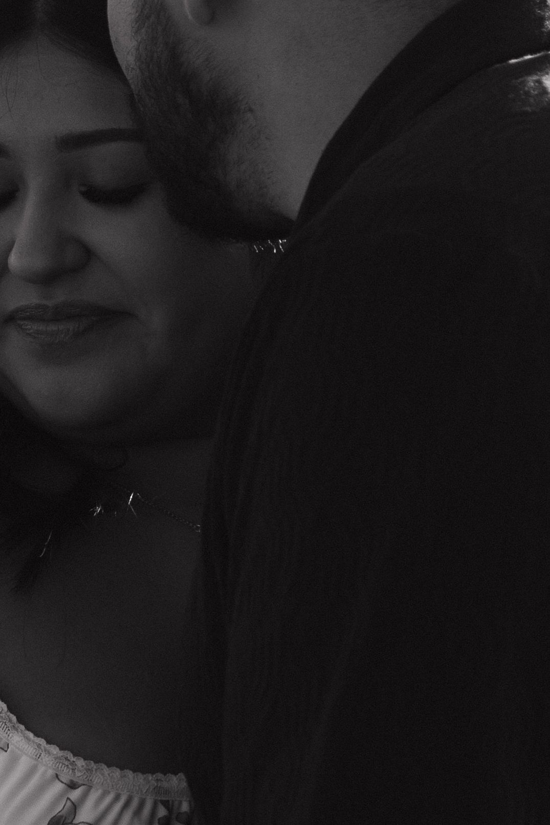 Black and white closeup portrait showing a serene expression and soft lighting in an intimate moment.
