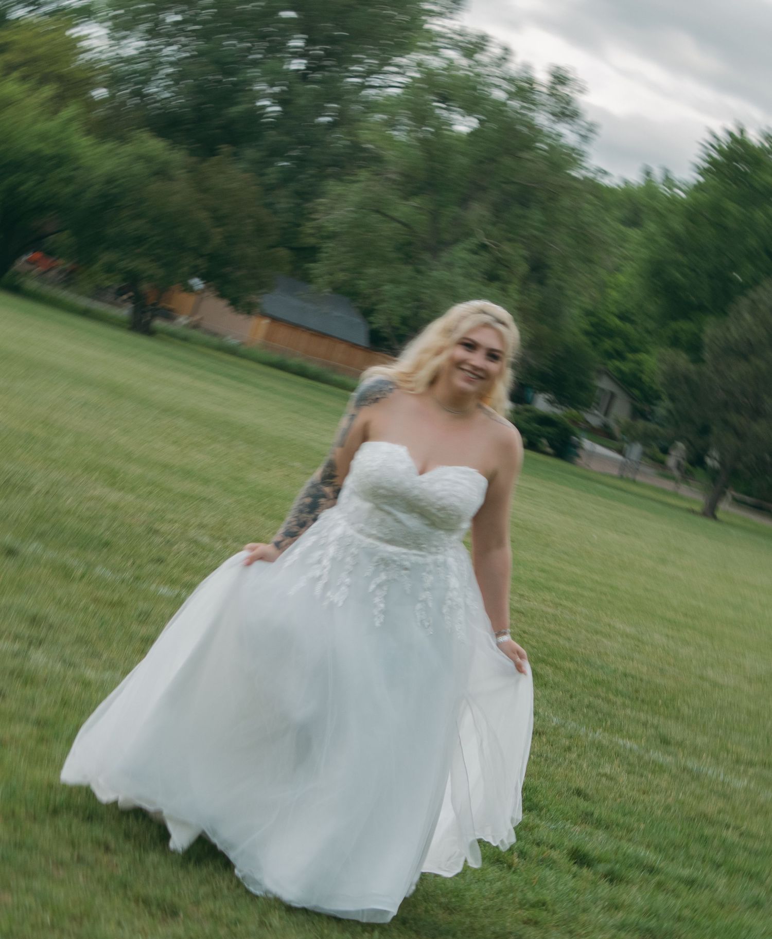 A flowing white wedding dress twirls gracefully in an outdoor garden setting.