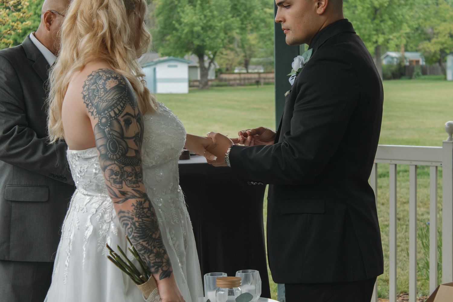 A couple stands in formal wedding attire during their outdoor pavilion ceremony.