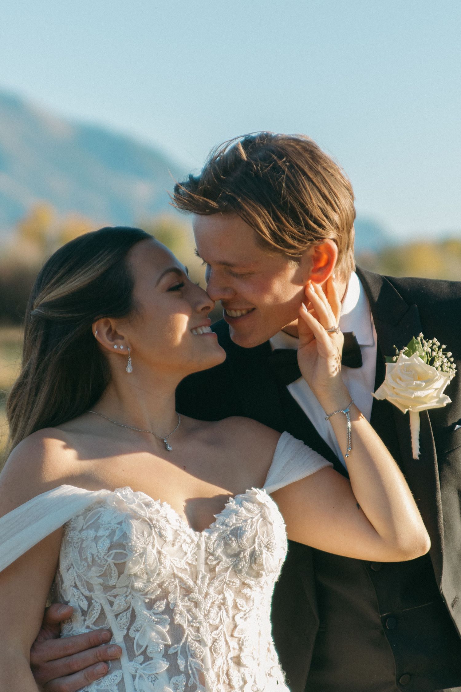 Romantic wedding couple embracing against a scenic mountain backdrop during golden hour.