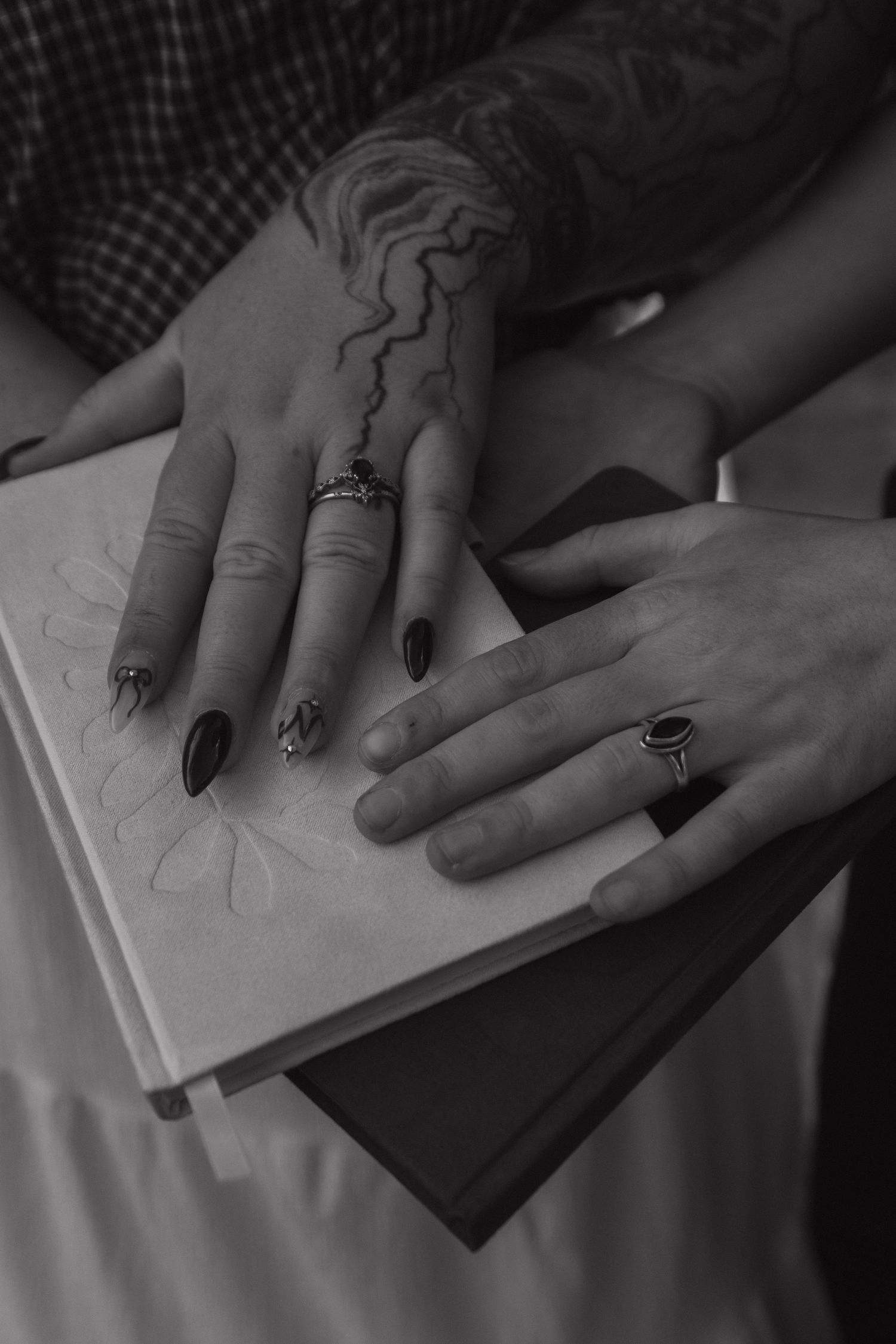 Black and white photo series showing hands with painted nails tracing or drawing lines on white paper.