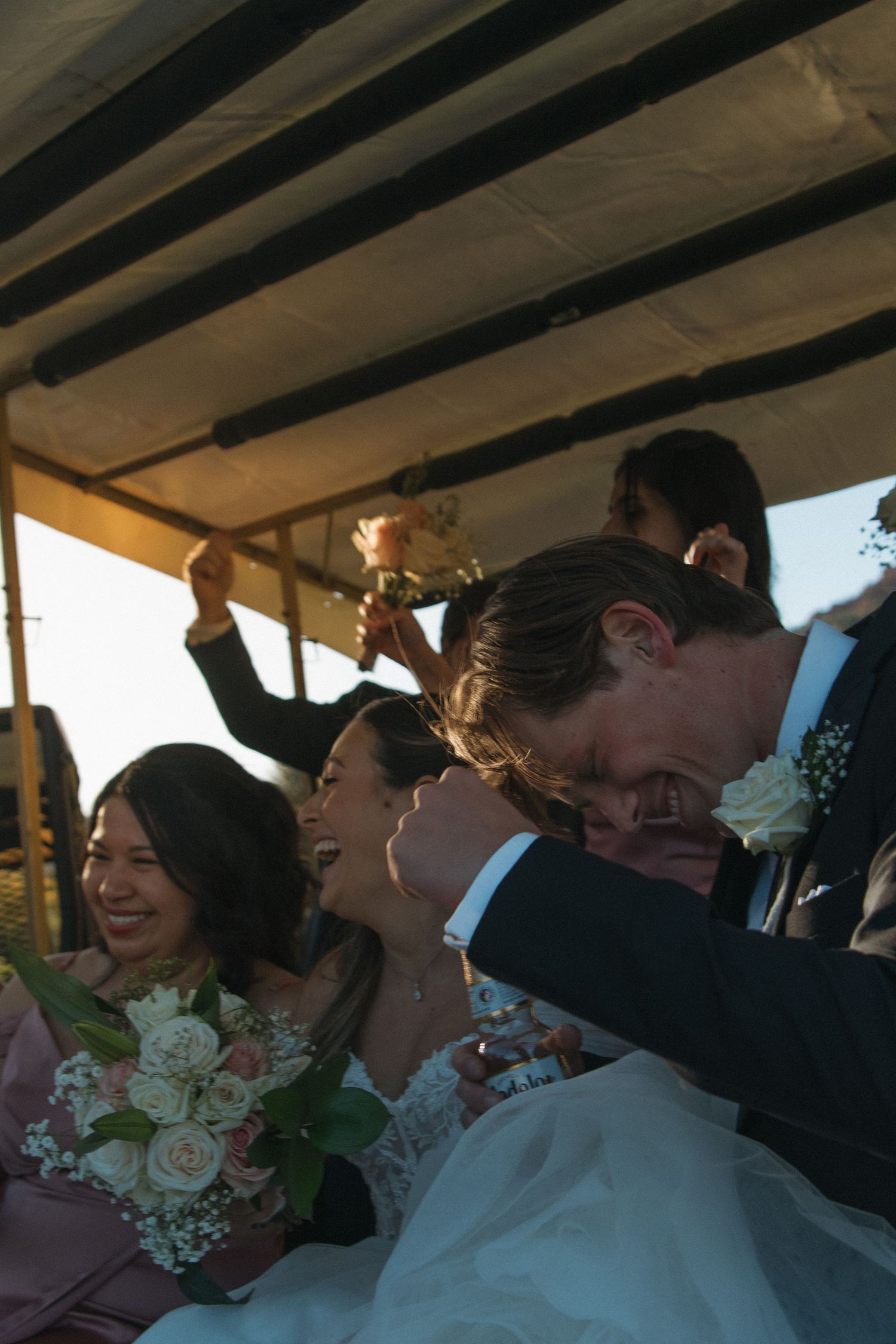 Wedding party guests share joyful laughter while seated together at a reception table with white floral decorations.