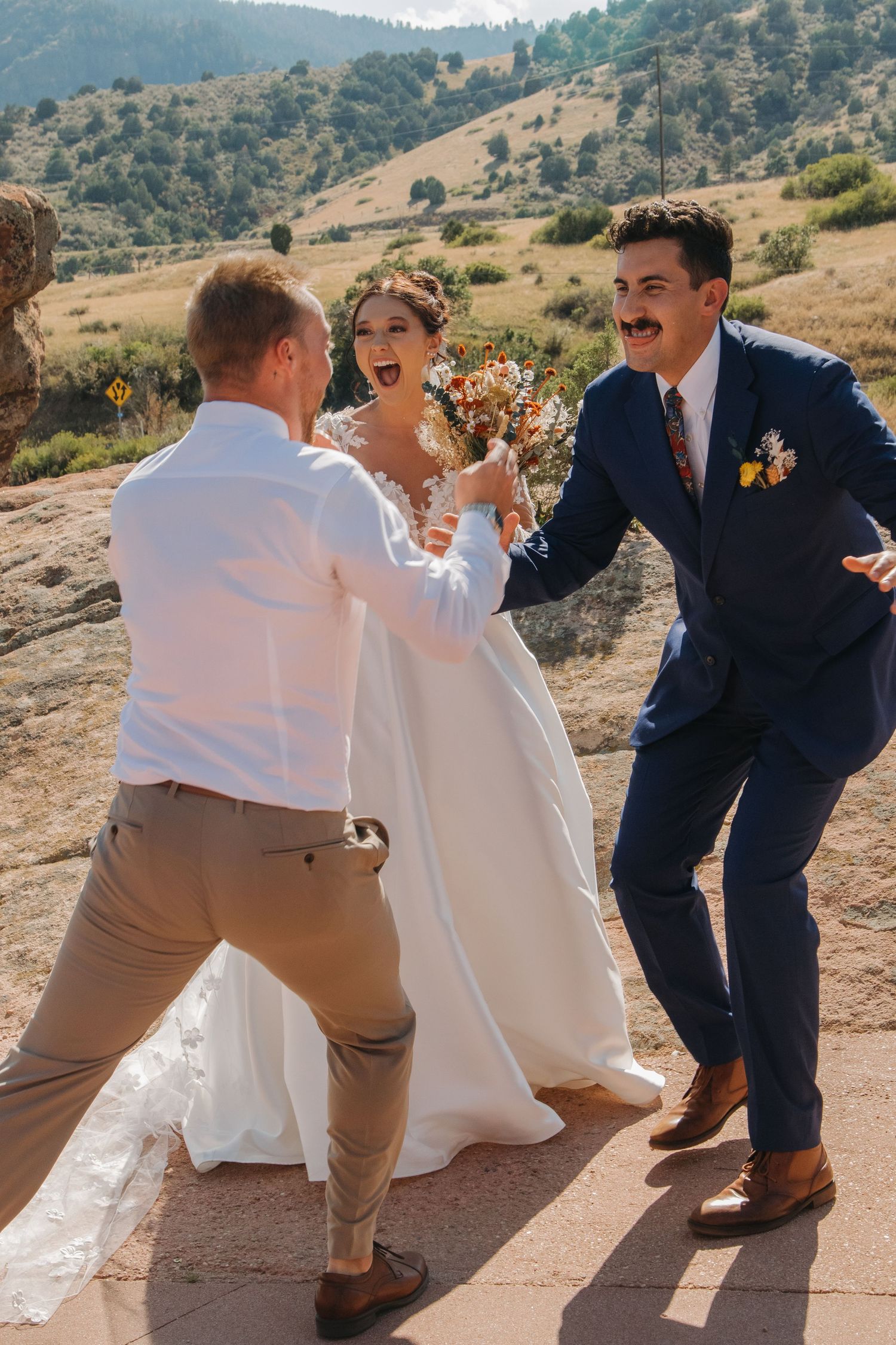 Wedding party celebrating and dancing on a mountain terrace at sunset.