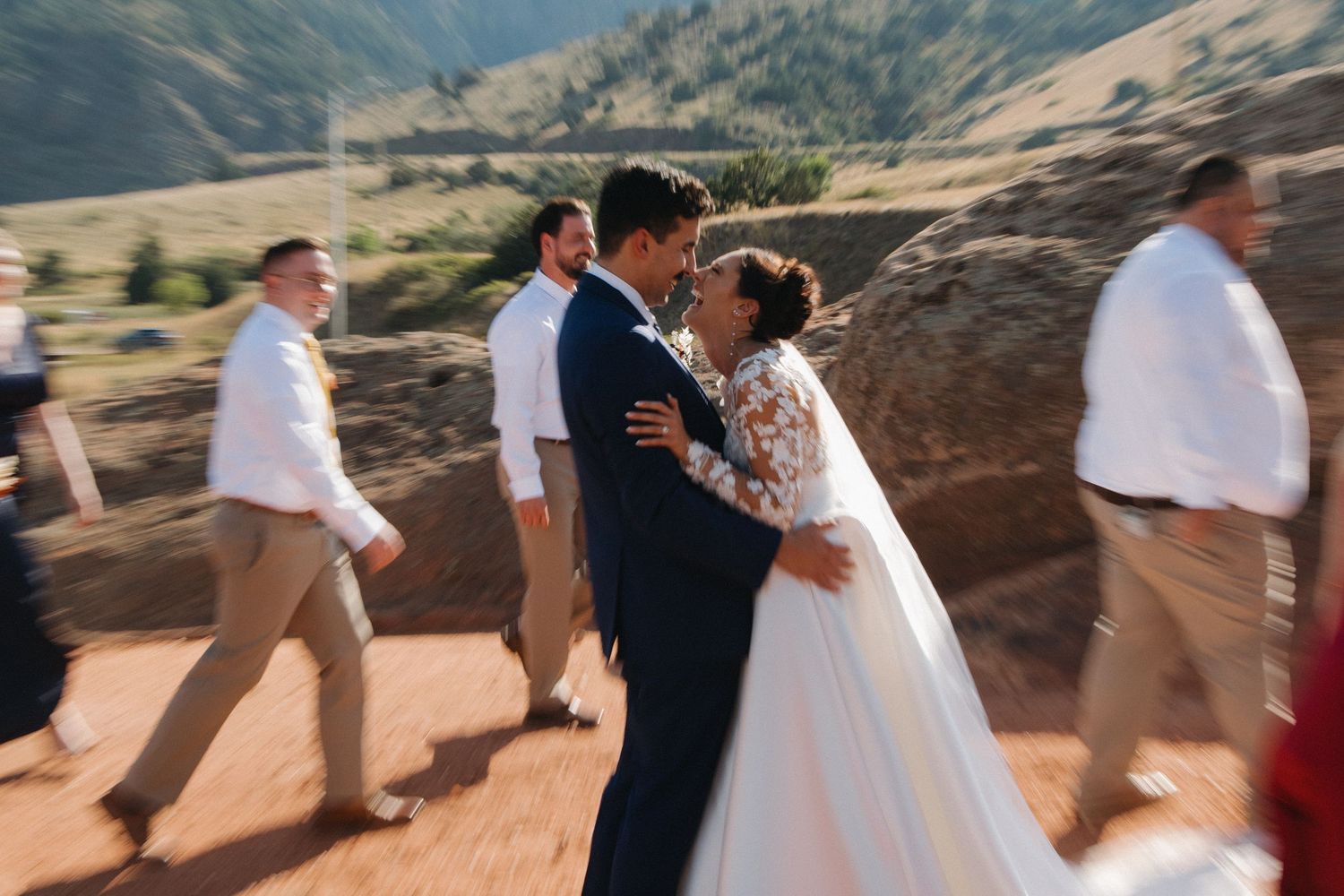 Wedding party walking and laughing together on a scenic mountain path.