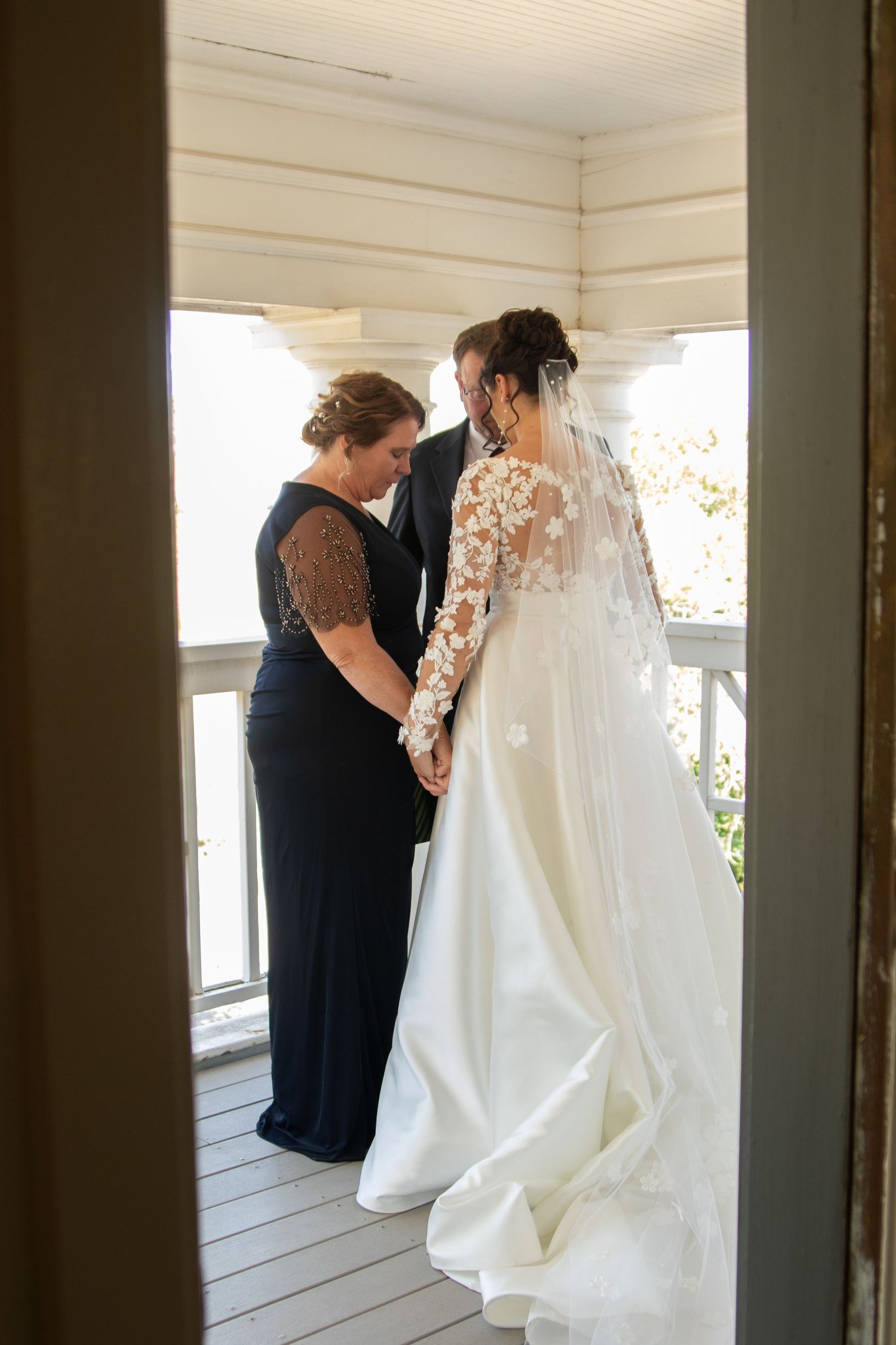 A wedding dress fitting moment on a porch shows intricate lace sleeves and a flowing white gown.