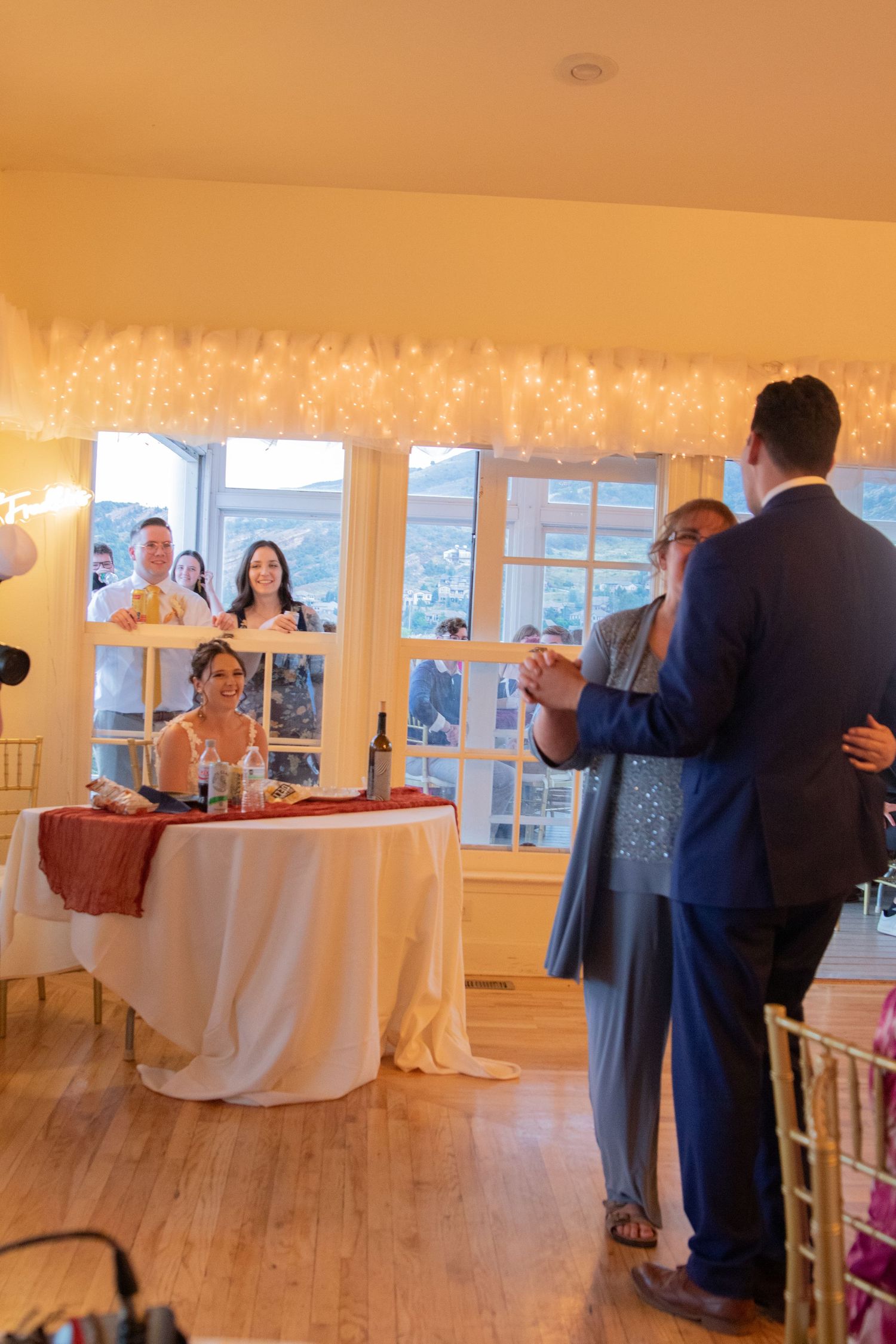 Wedding reception in a warmly lit room with string lights and elegant decor.