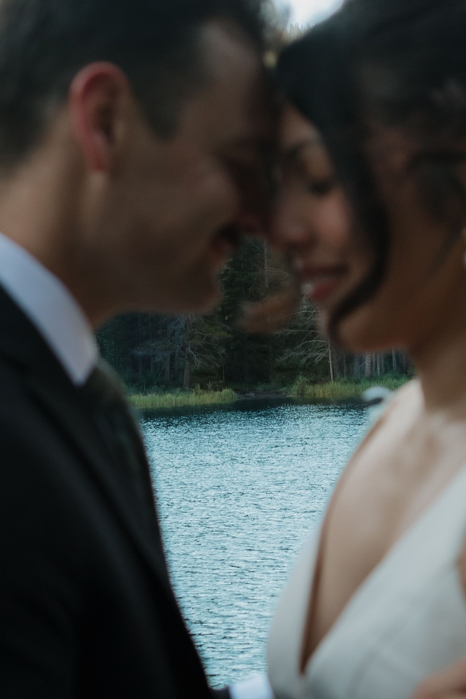 An intimate wedding moment captured by a serene mountain lake at dusk.