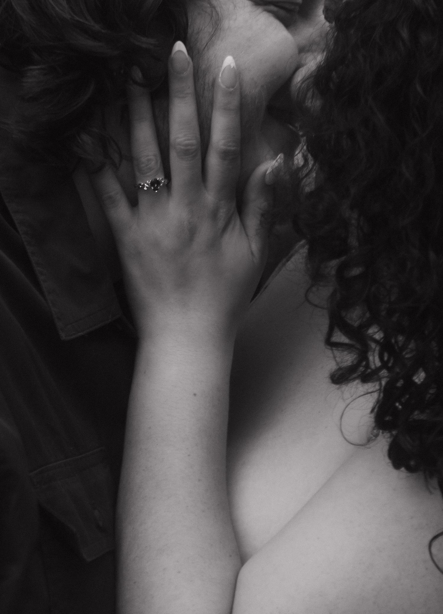 A close-up monochrome photograph shows a raised hand gently emerging from dark shadows.