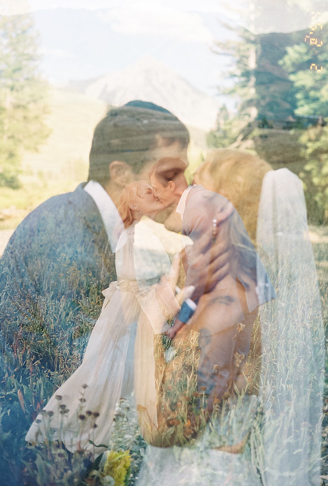 Dreamy double exposure of bride and groom kissing set against a lush mountain forest landscape.