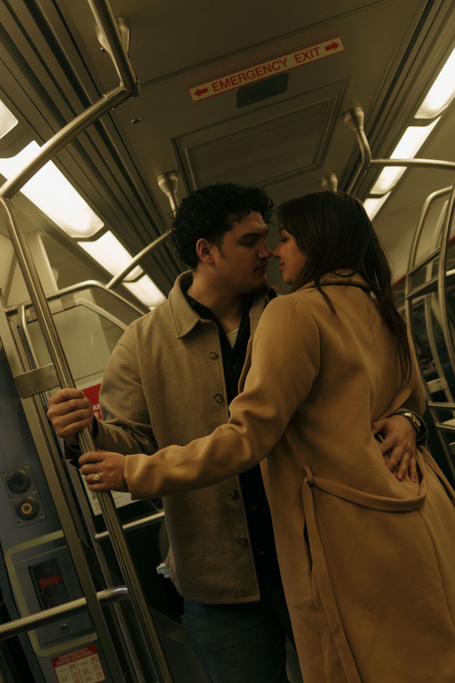 A couple shares an intimate moment while standing in a subway train car.