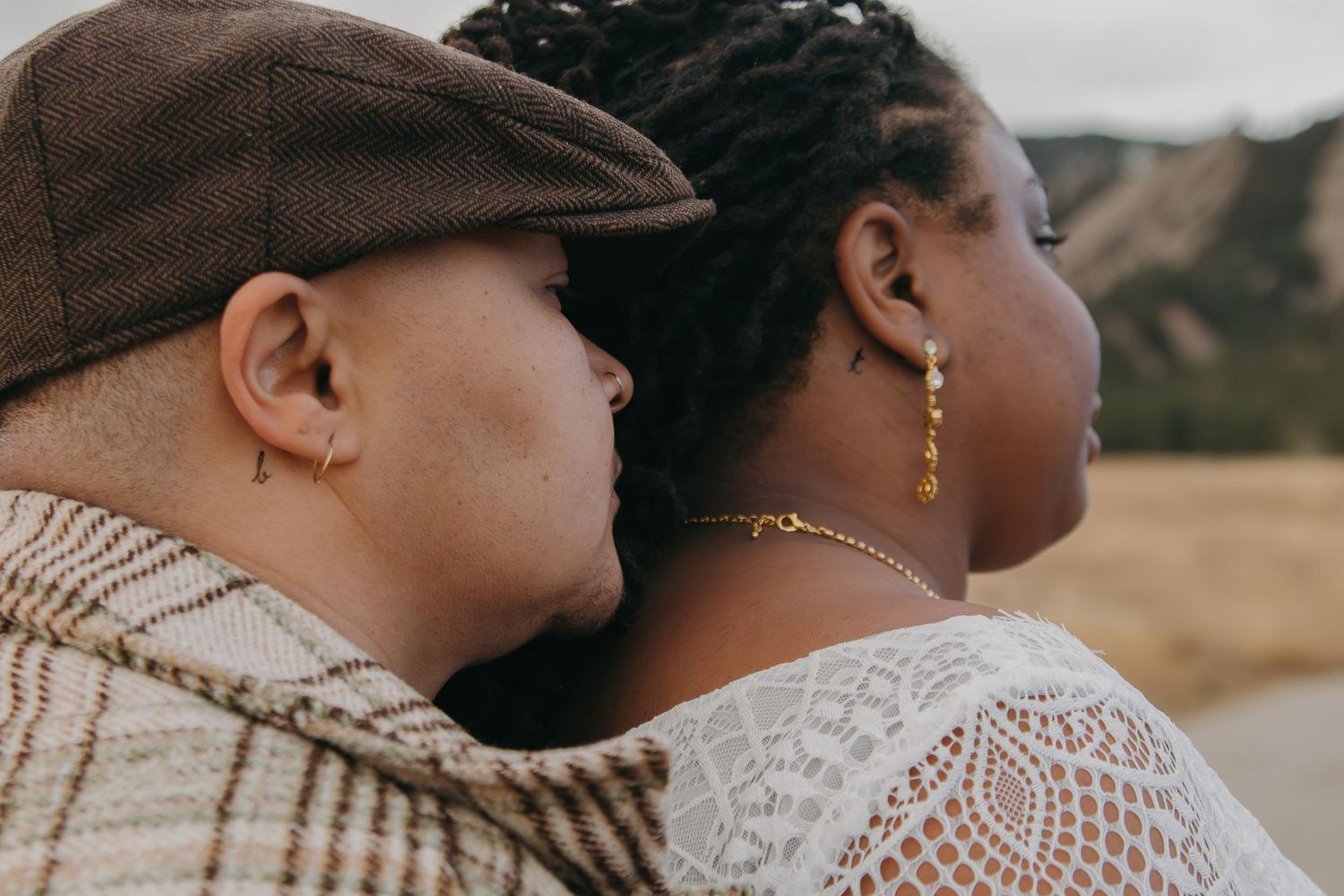 A couple embraces in a tender moment outdoors while wearing cozy knit sweaters on a misty autumn day.