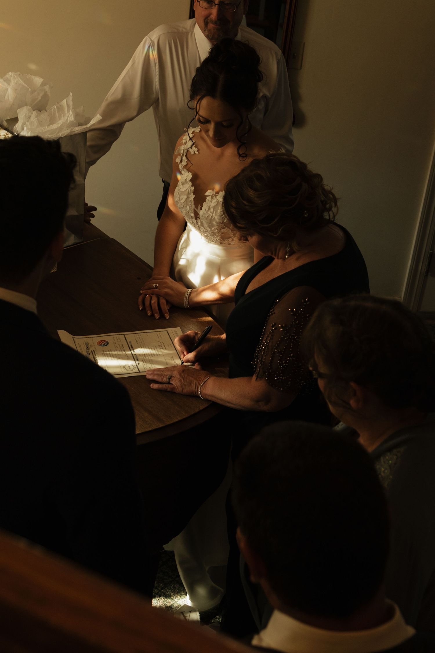 Two figures writing by candlelight in a dimly lit room create an intimate artistic atmosphere.