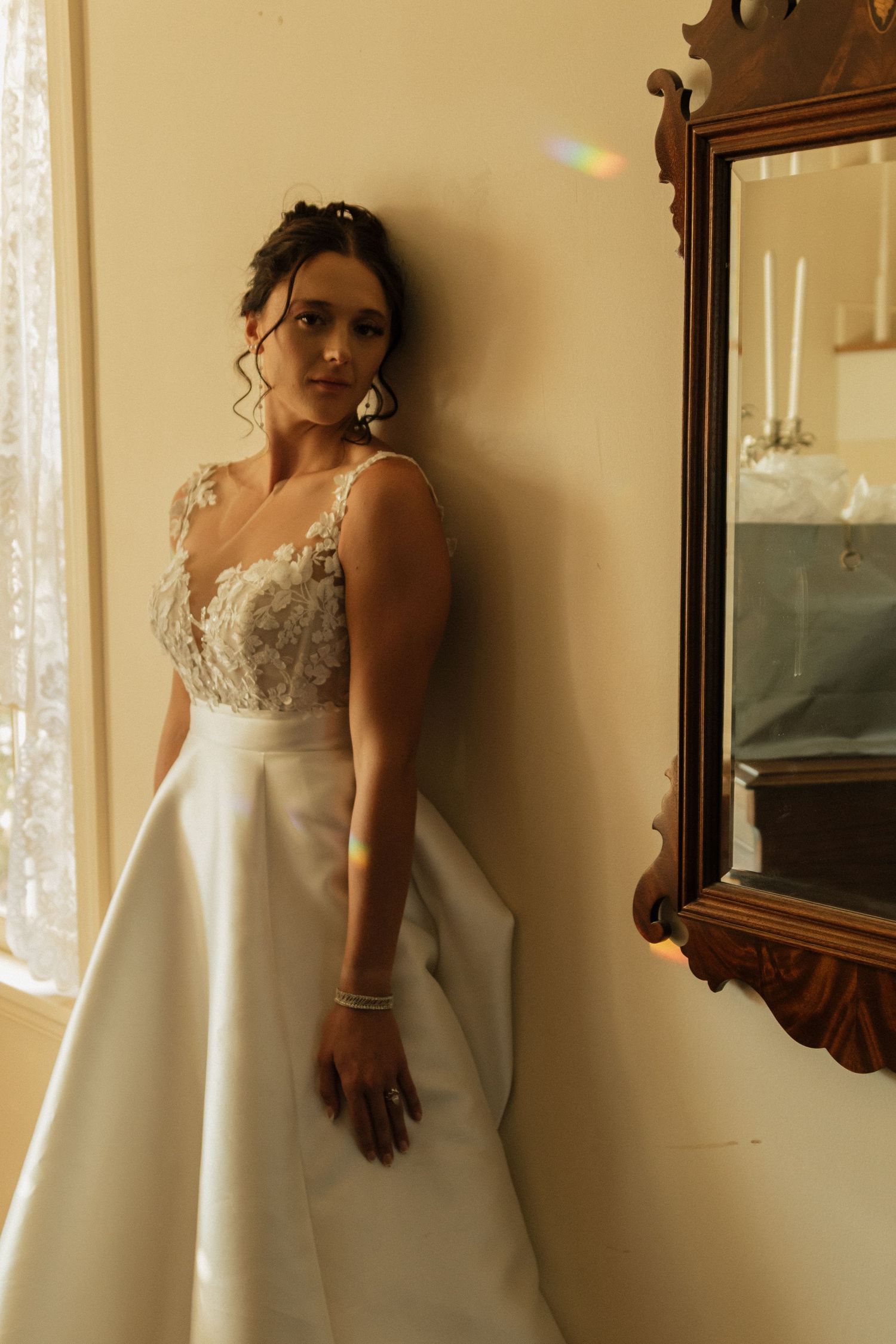 Elegant wedding dress details reflected in vintage mirror with soft lighting.