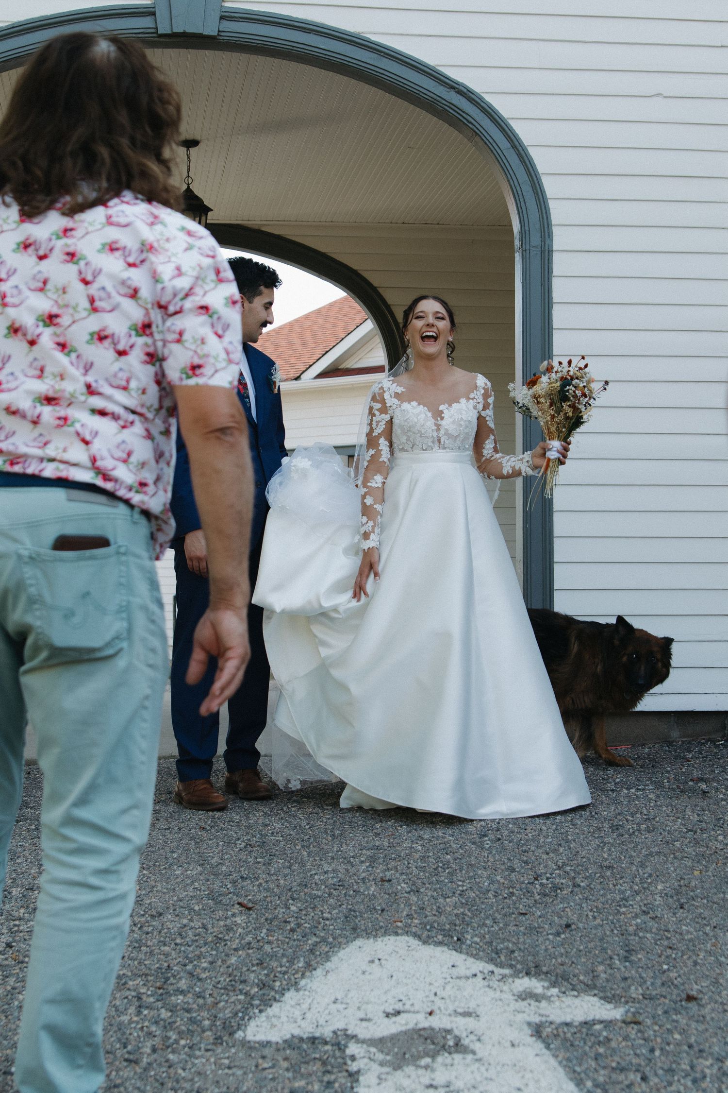 Bride in elegant lace gown standing under an archway entrance.