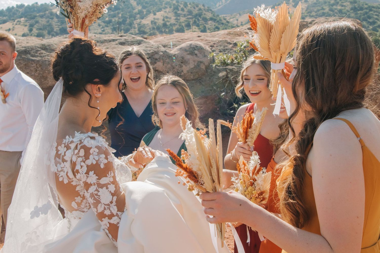 Wedding party celebrates outdoors with sparklers during a sunny daytime celebration.