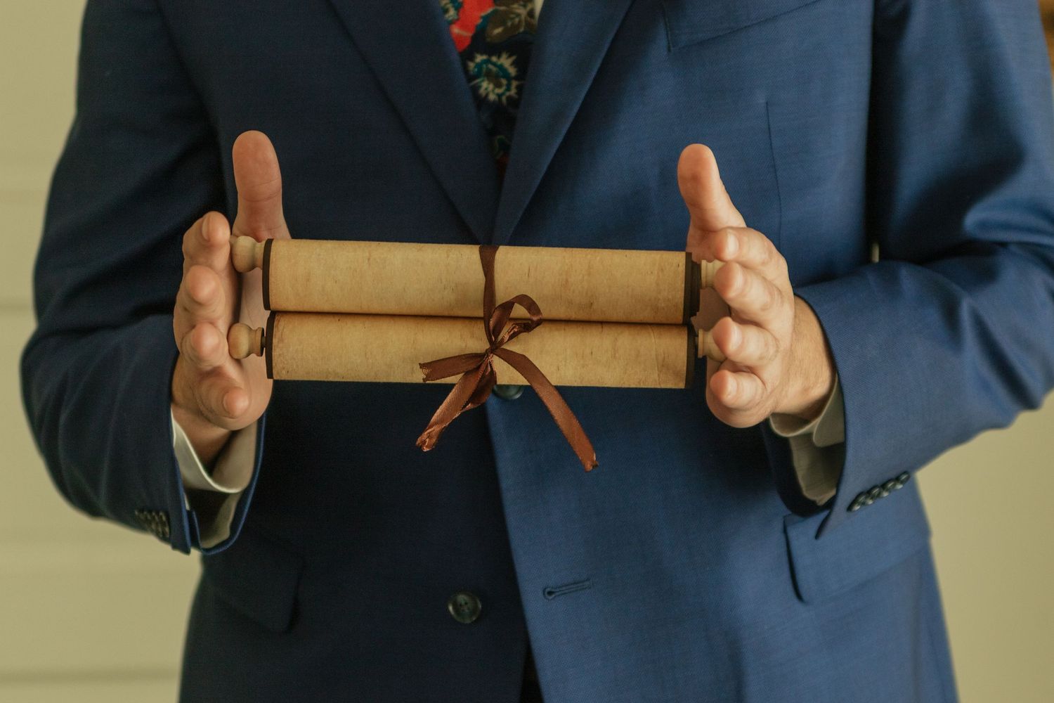 Hands holding and opening a wrapped package with brown paper and string.
