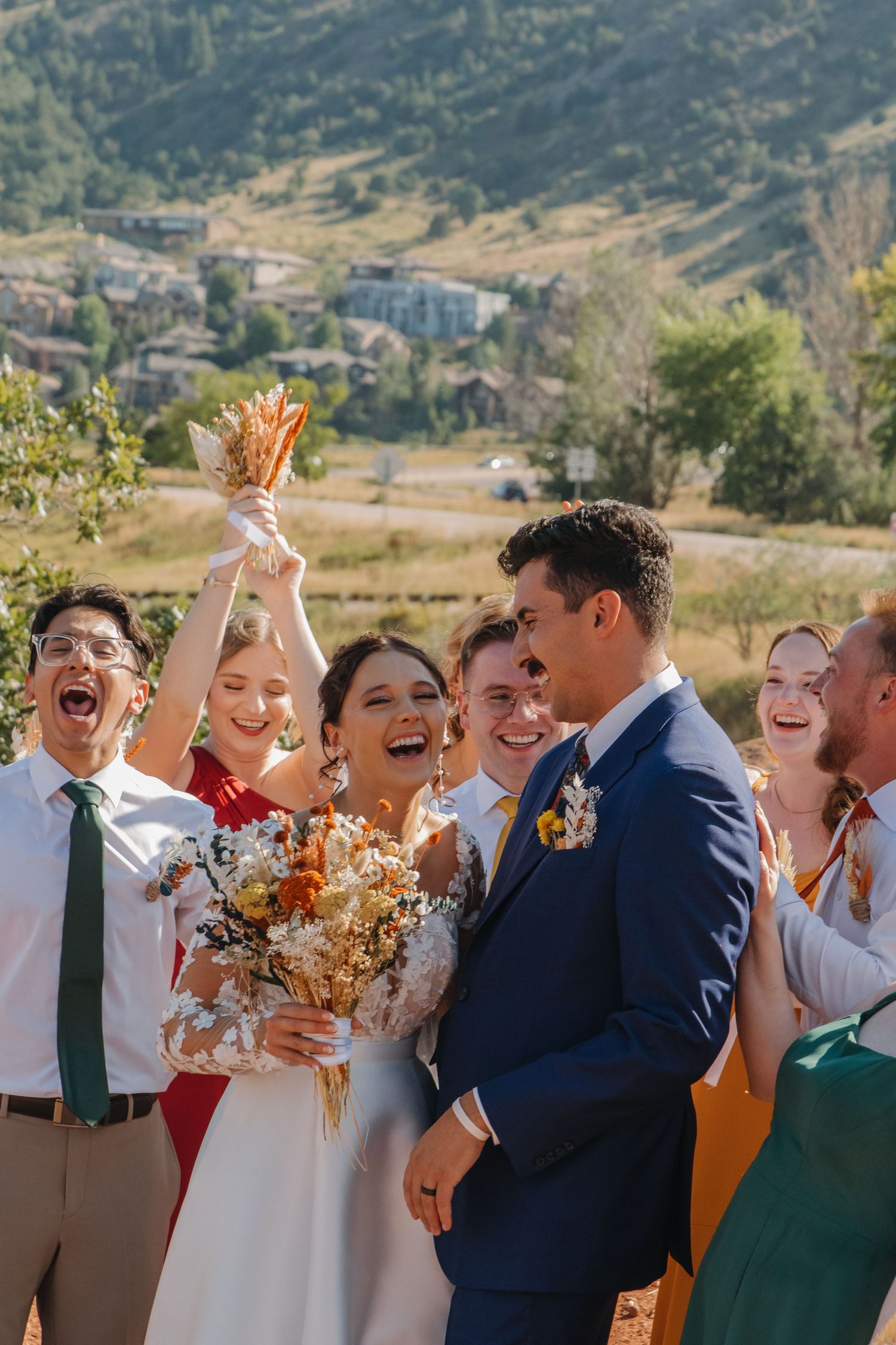 Wedding party celebrating with joyful expressions against mountain landscape.