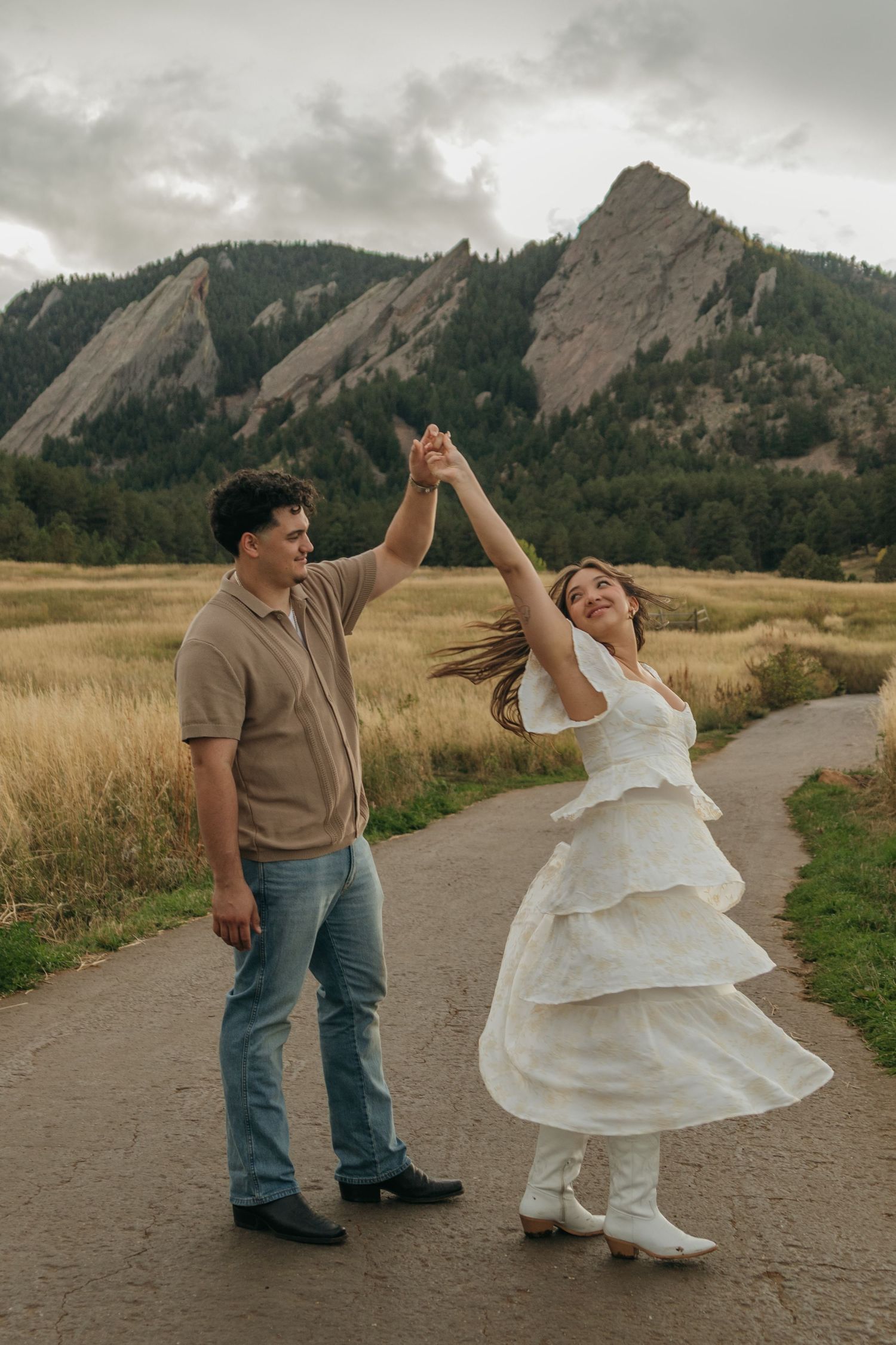 Couple dancing on a path with the iconic Flatirons mountain backdrop in Boulder, CO.