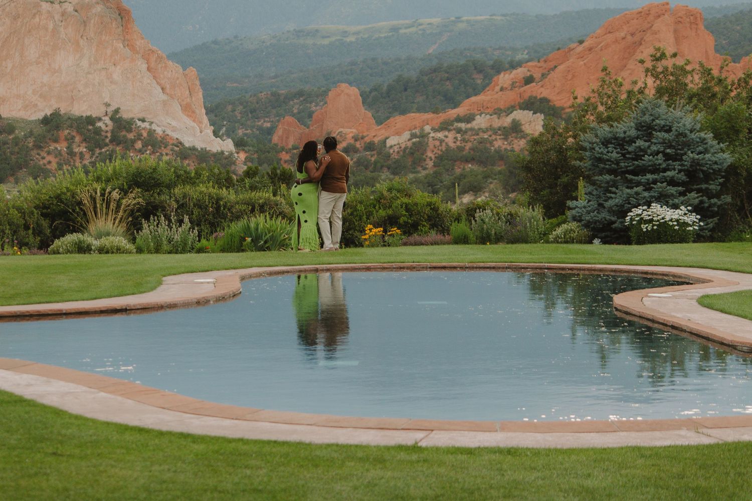 Couple reflected in heart-shaped pool at Garden of the Gods with red rocks in background.
