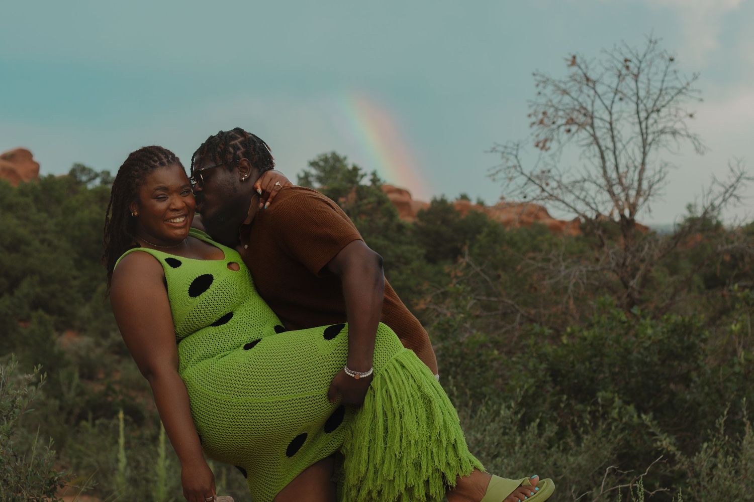Playful engagement photo with rainbow visible in background at Garden of the Gods.