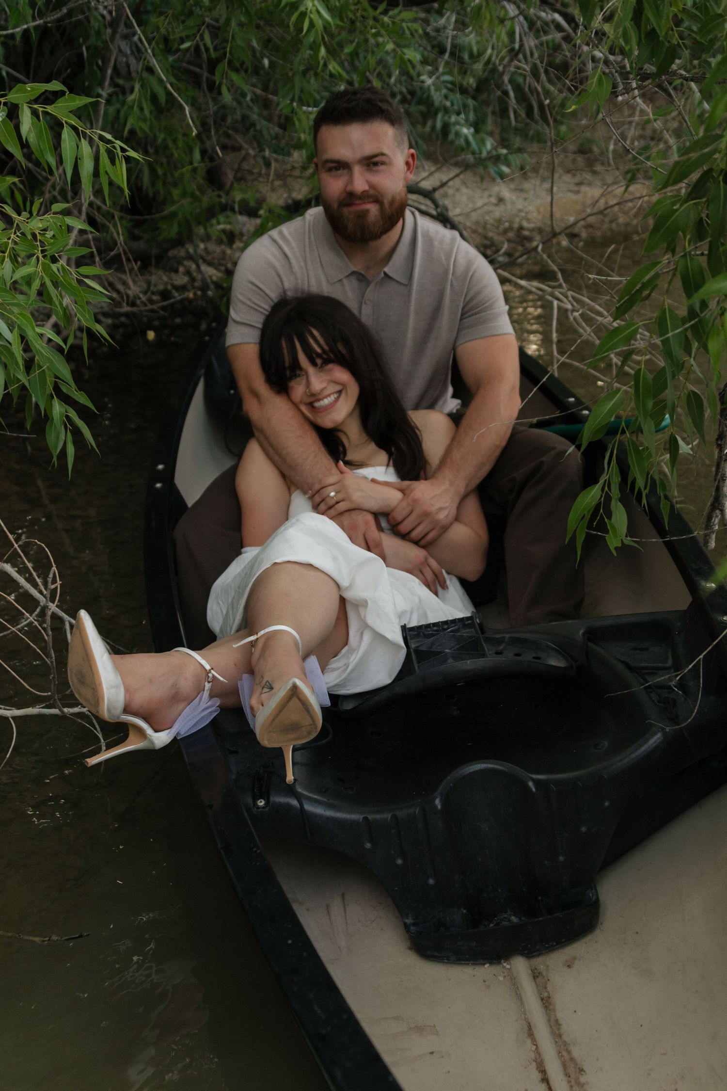 Two people share romantic moments in a small boat surrounded by greenery.