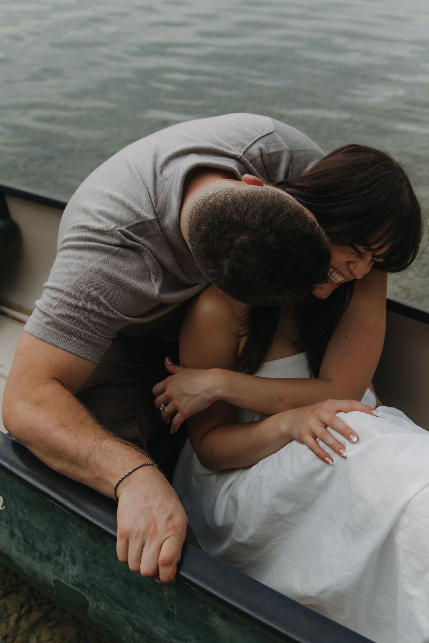 Tender embrace captured in canoe with rippling water backdrop.