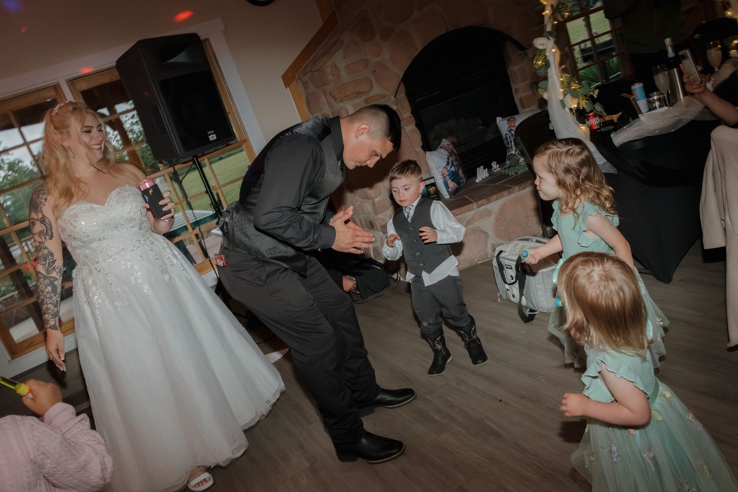 Guests dance and celebrate with children at an indoor wedding reception.
